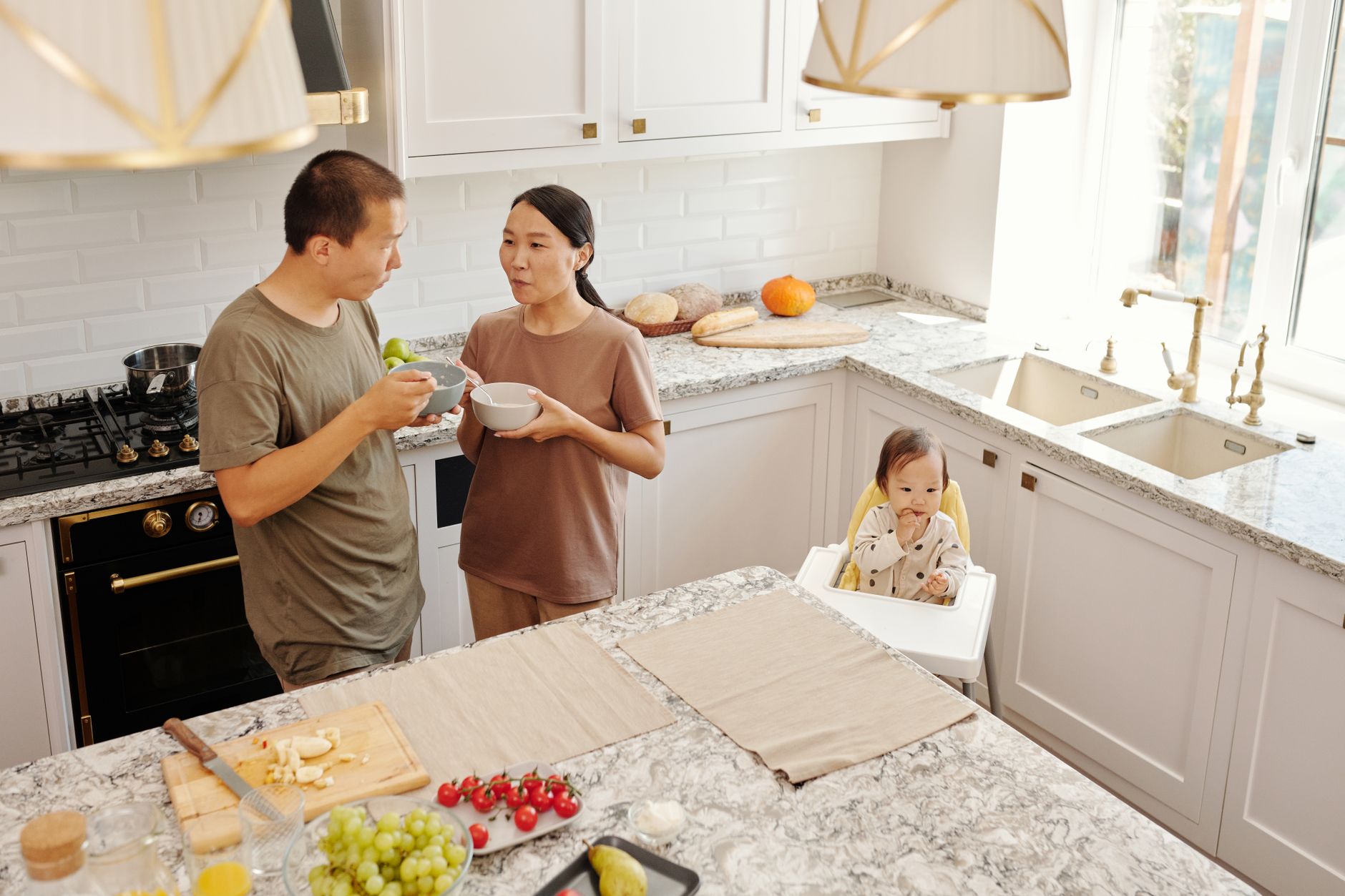 Couple cooking together with baby in carrier.