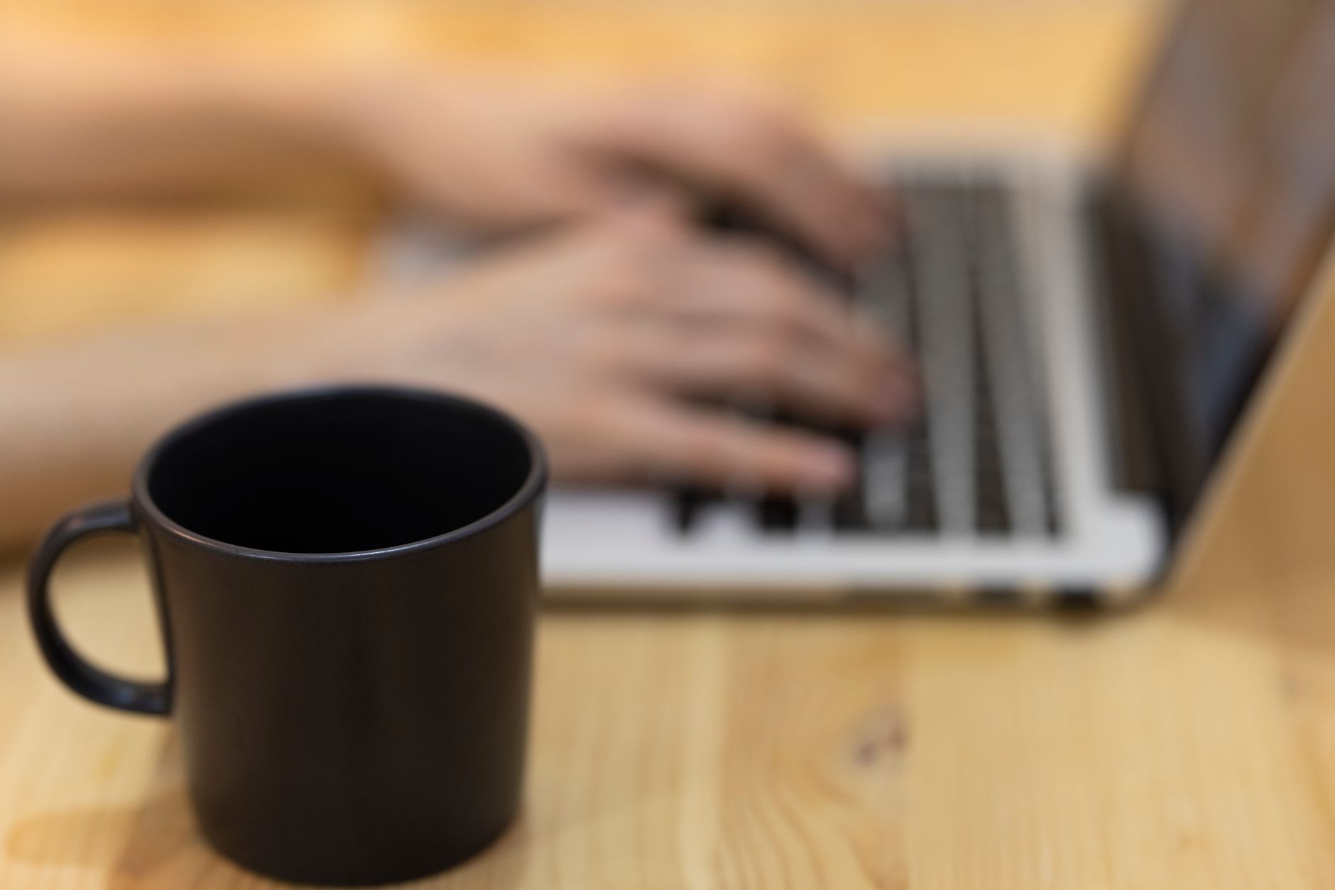 A calm mother sitting at a kitchen table with a laptop open to a mental‑health portal, a cup of tea beside her, soft morning light streaming through the window