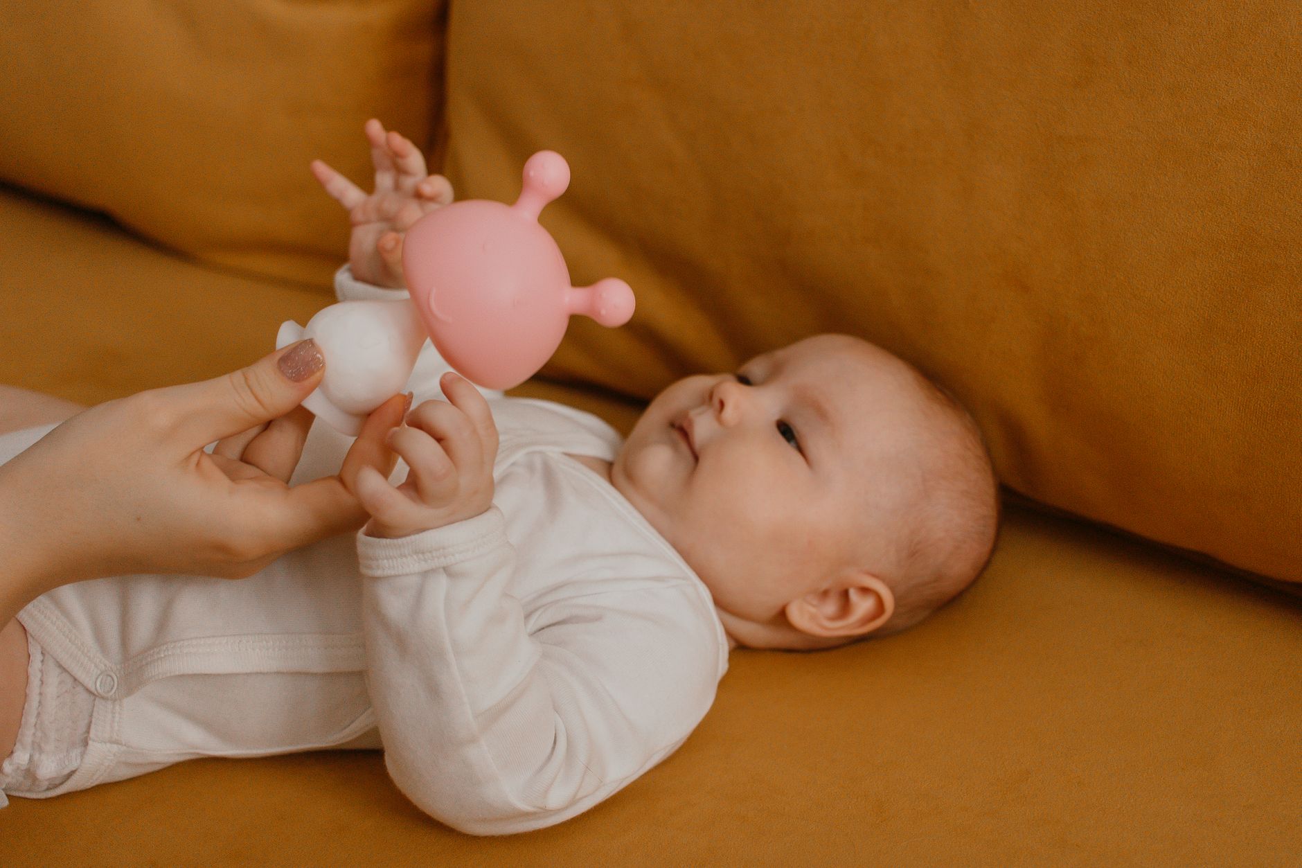A parent holding a baby, with a growth chart on the wall in the background, showing a family at home