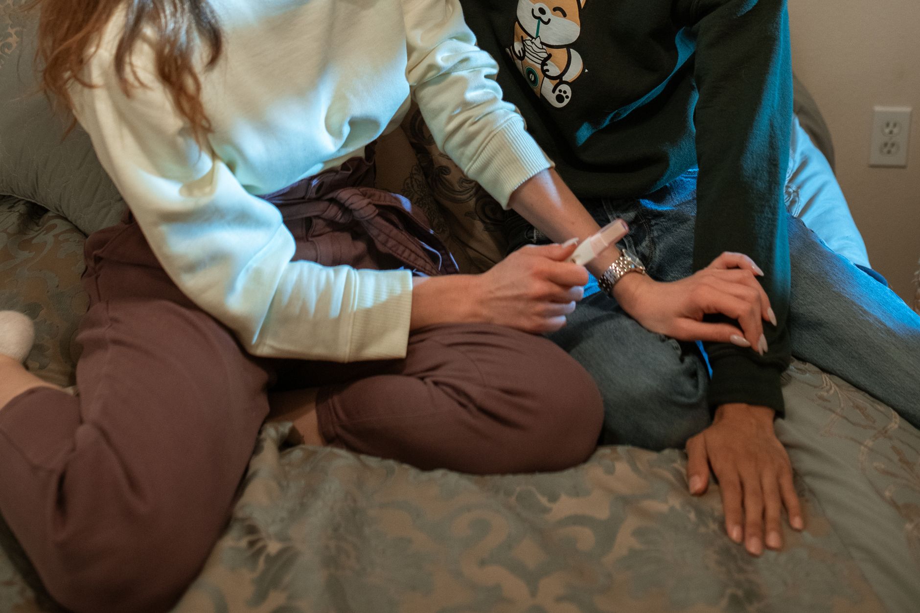 a hand holding a small tube of Abreva next to a pregnancy test on a bedside table, soft natural lighting, calm bedroom setting that emphasizes reassurance for new mothers