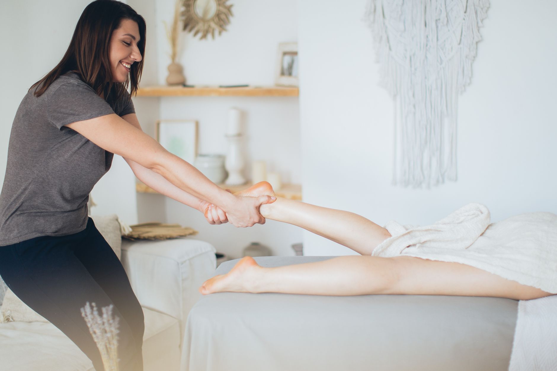 A pregnant woman receiving a gentle foot massage, with soft lighting and a focus on her feet and the therapist's hands, illustrating safe touch.