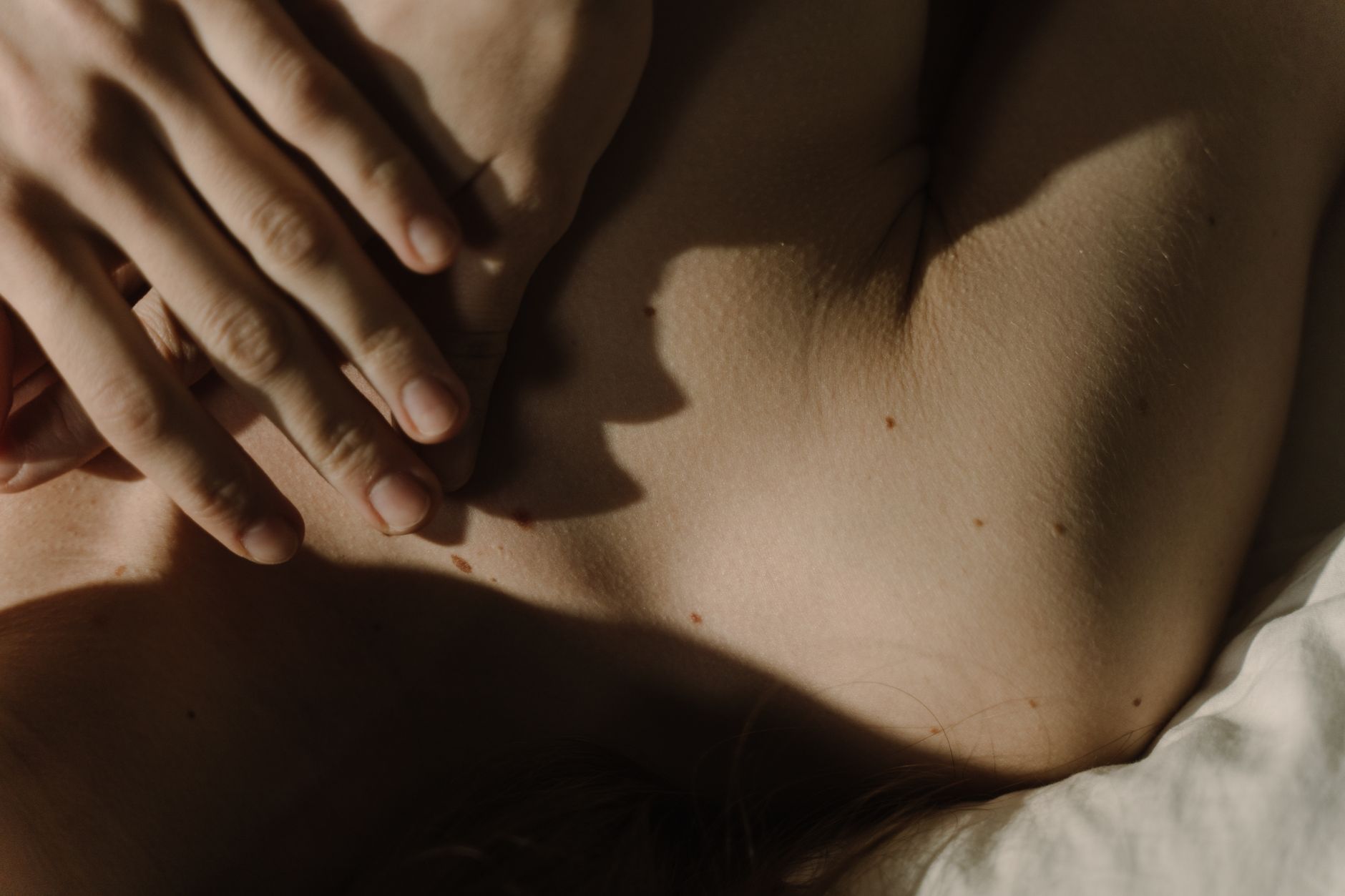 A close-up of a pregnant person’s hands receiving acupressure on the P6 (Nei Guan) point for nausea relief, with a gentle touch and a calm expression