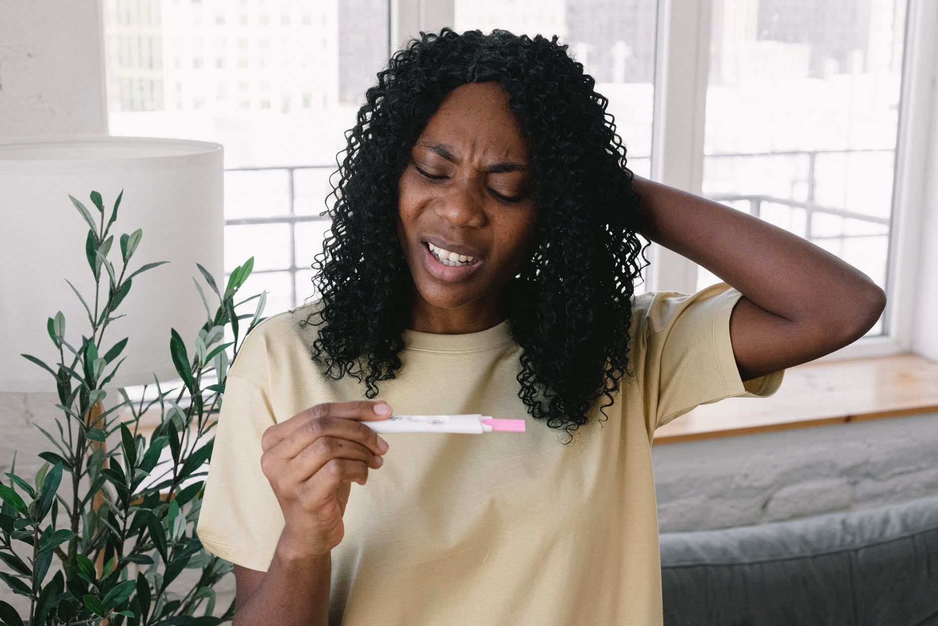 Pregnant woman holding a prenatal vitamin bottle and looking at the label with a thoughtful expression