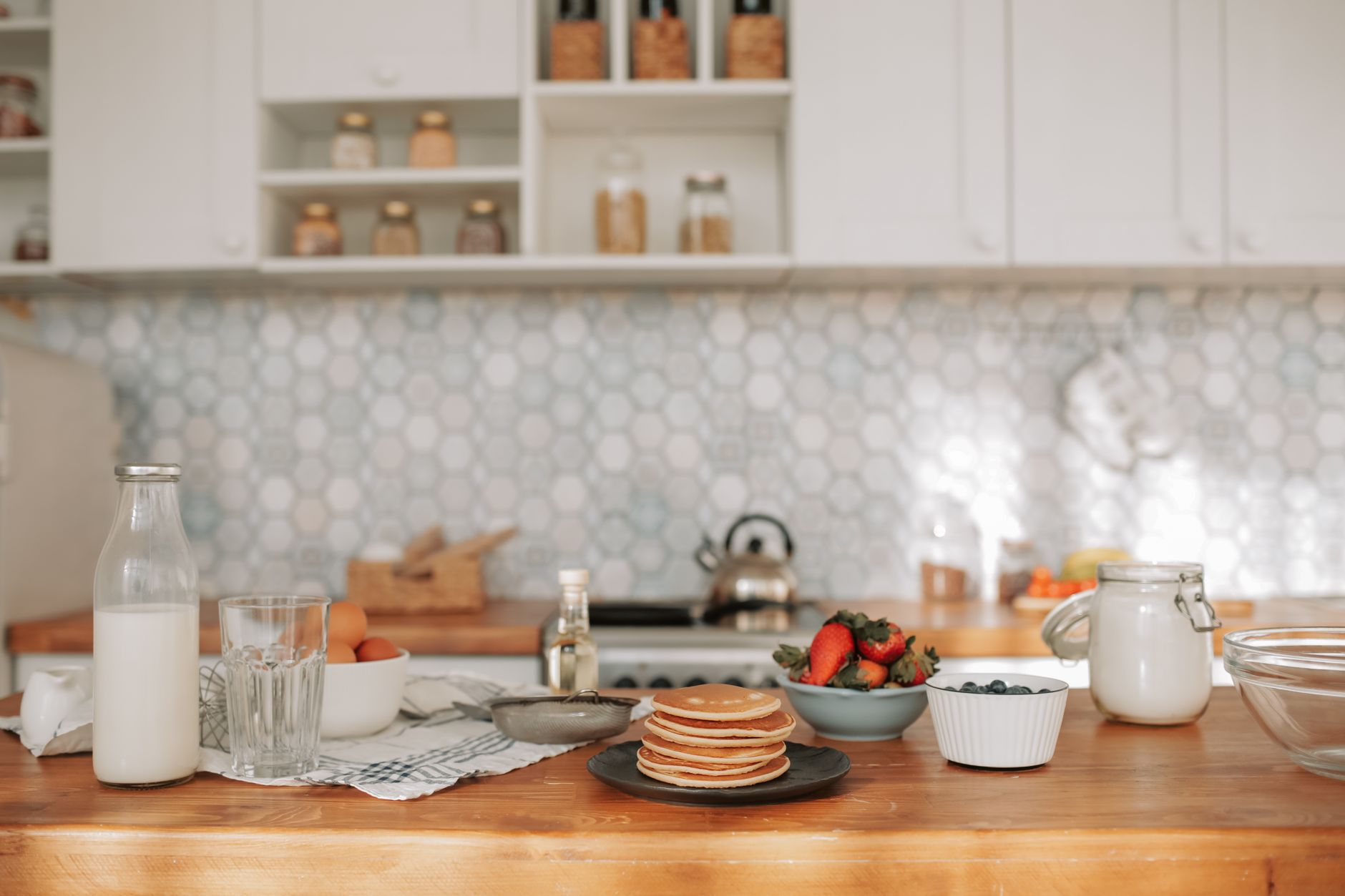 a kitchen countertop with a bowl of saline solution, a neti pot, and a small bottle of Nasonex nasal spray, bright natural light highlighting the items