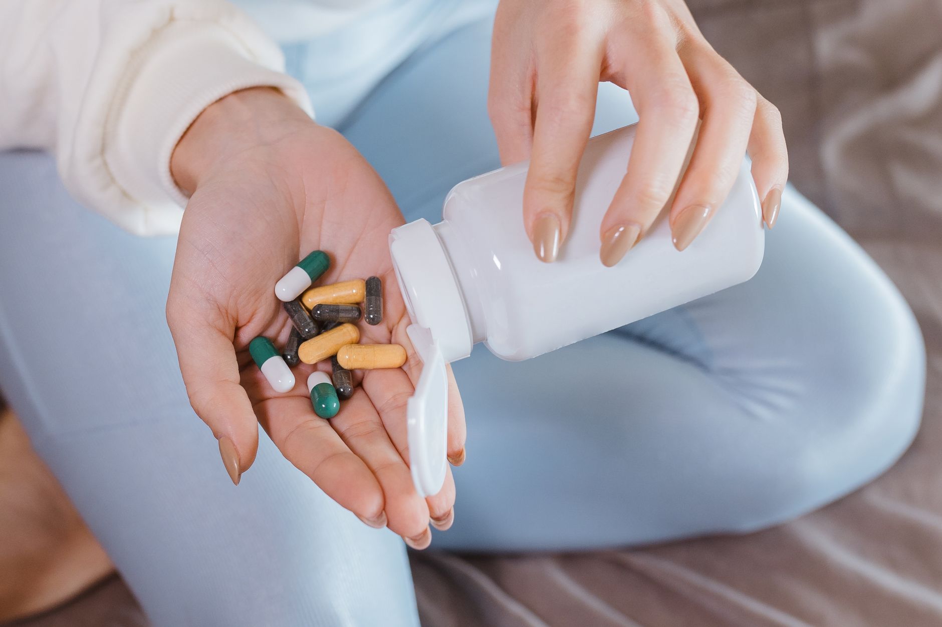 A hand holding a bottle of amoxicillin next to a pregnancy nutrition guide, illustrating the balance of medication and prenatal care