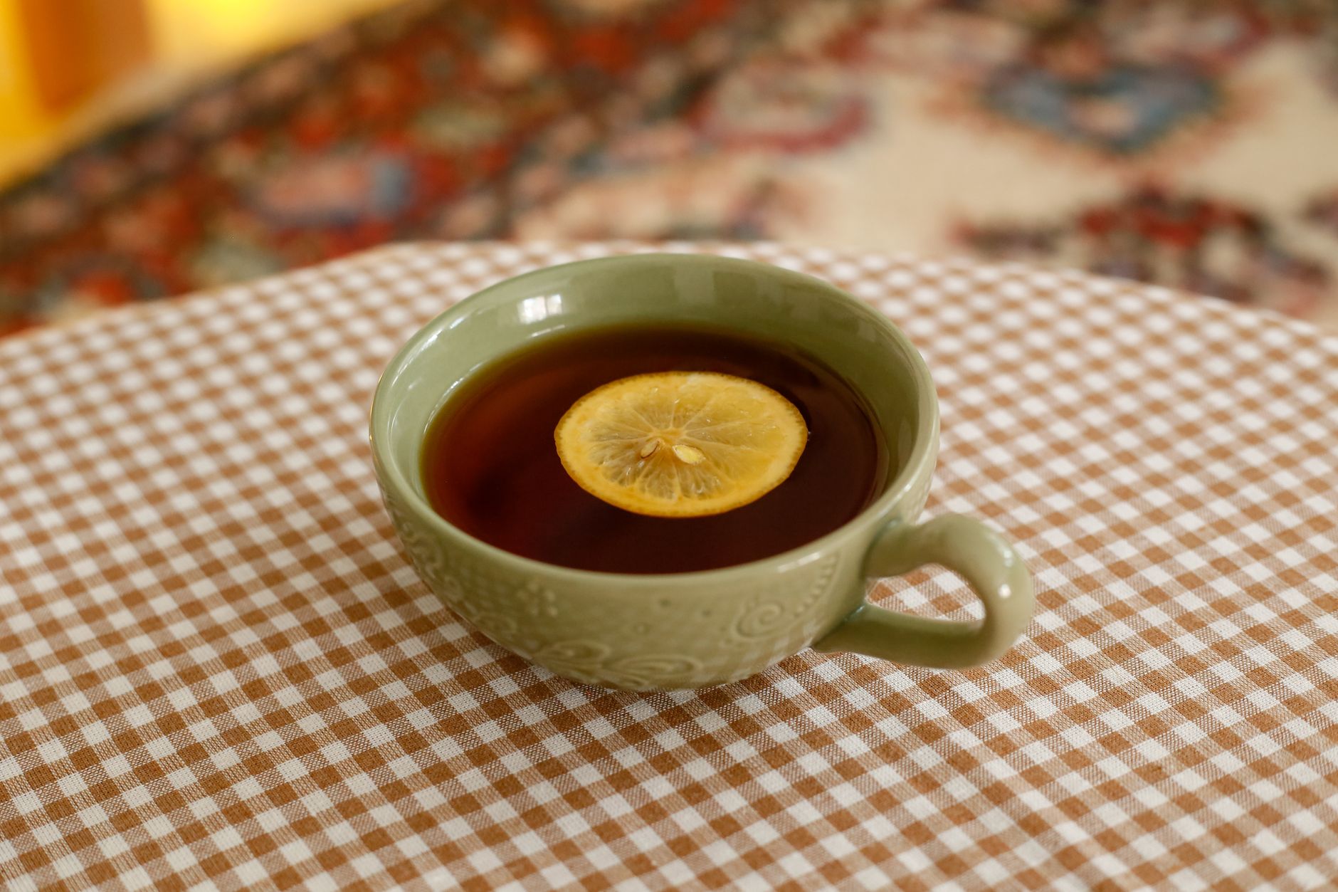 a close‑up of a glass of ginger tea with a lemon slice, placed on a wooden table beside a pregnancy handbook, natural light streaming in