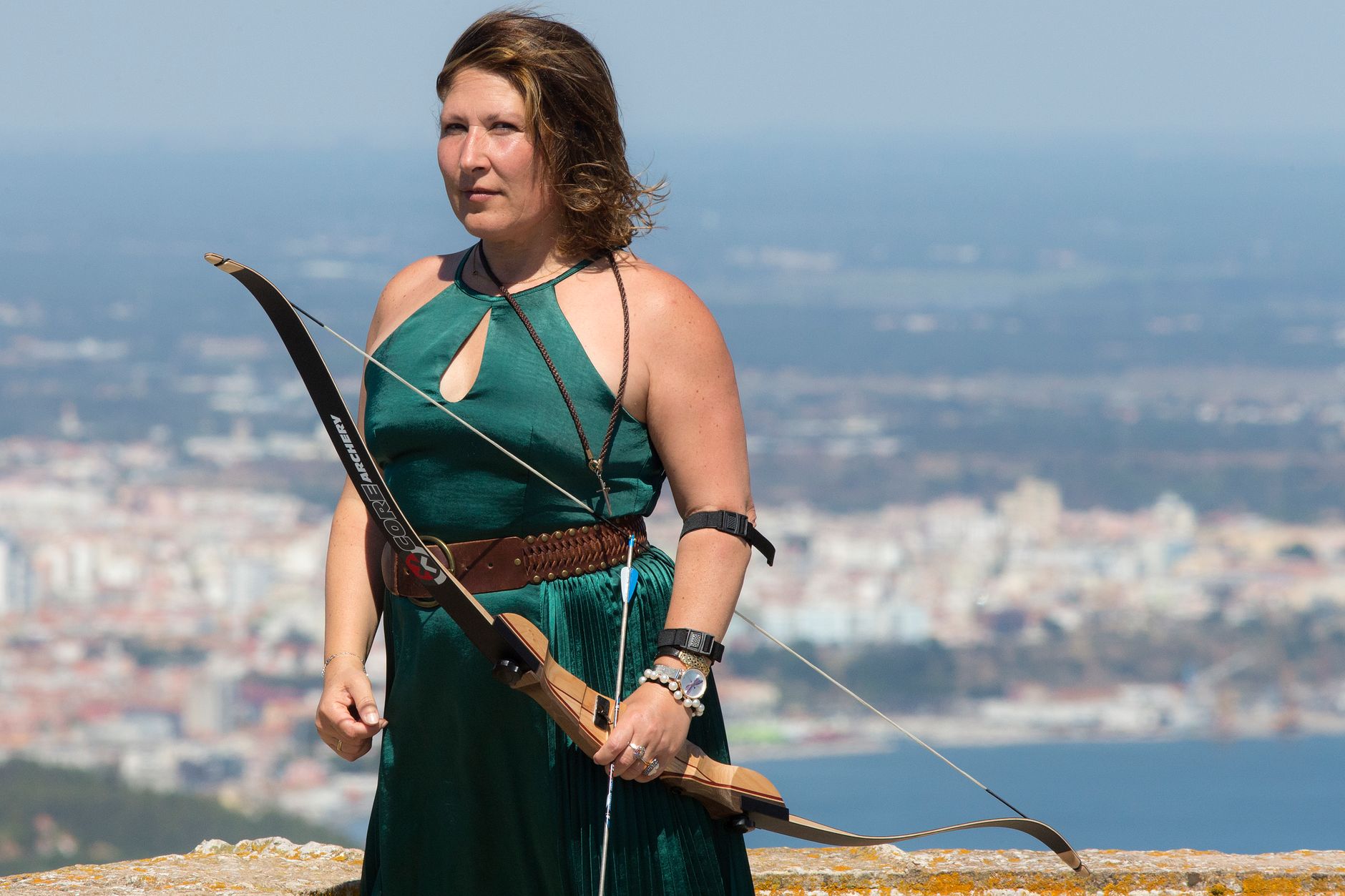pregnant woman wearing a belly guard while practicing archery at a range