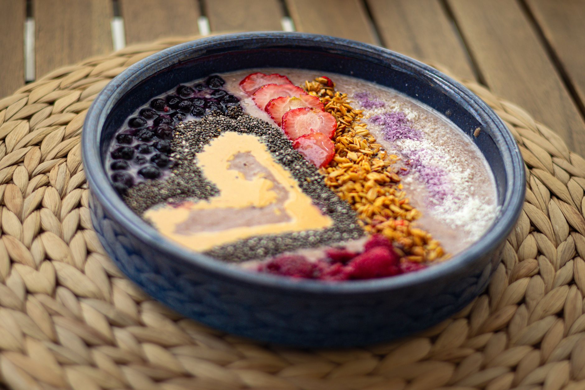 A pregnant woman holding a smoothie bowl with protein powder, berries, and nuts, illustrating a nutrient‑dense breakfast option