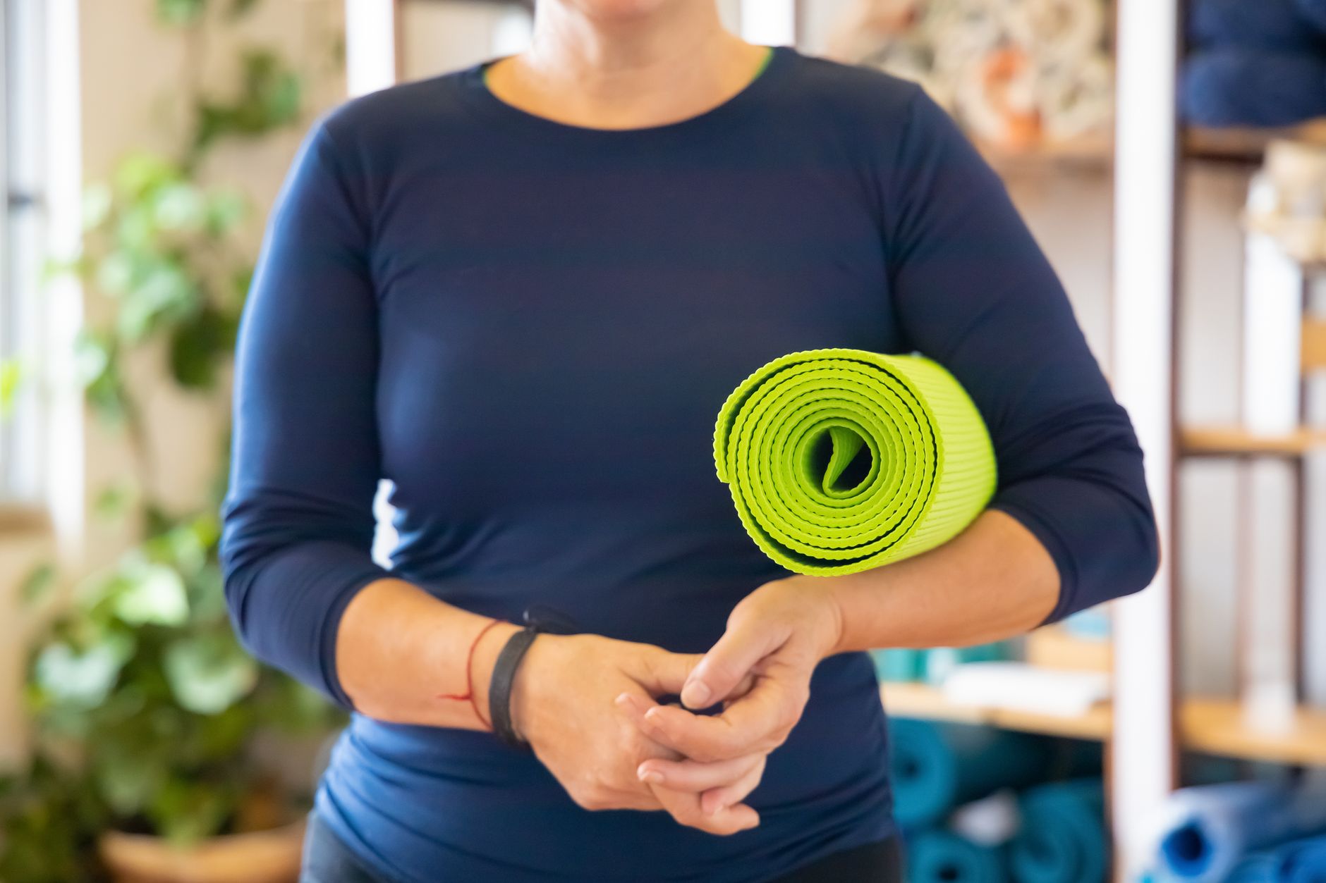 close-up of a pregnant woman's hands holding a prenatal yoga mat outdoors