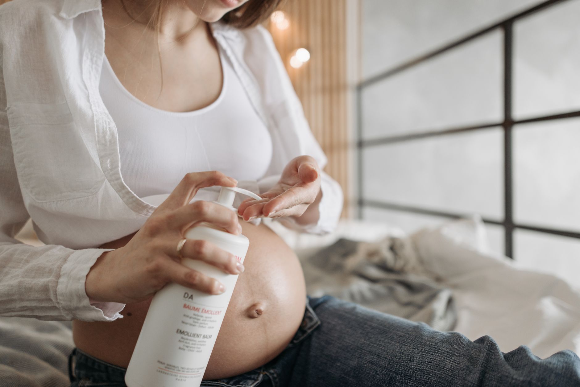 A close‑up of a pregnant belly with a thin layer of moisturizer being applied, showing gentle care and safe usage of a topical cream