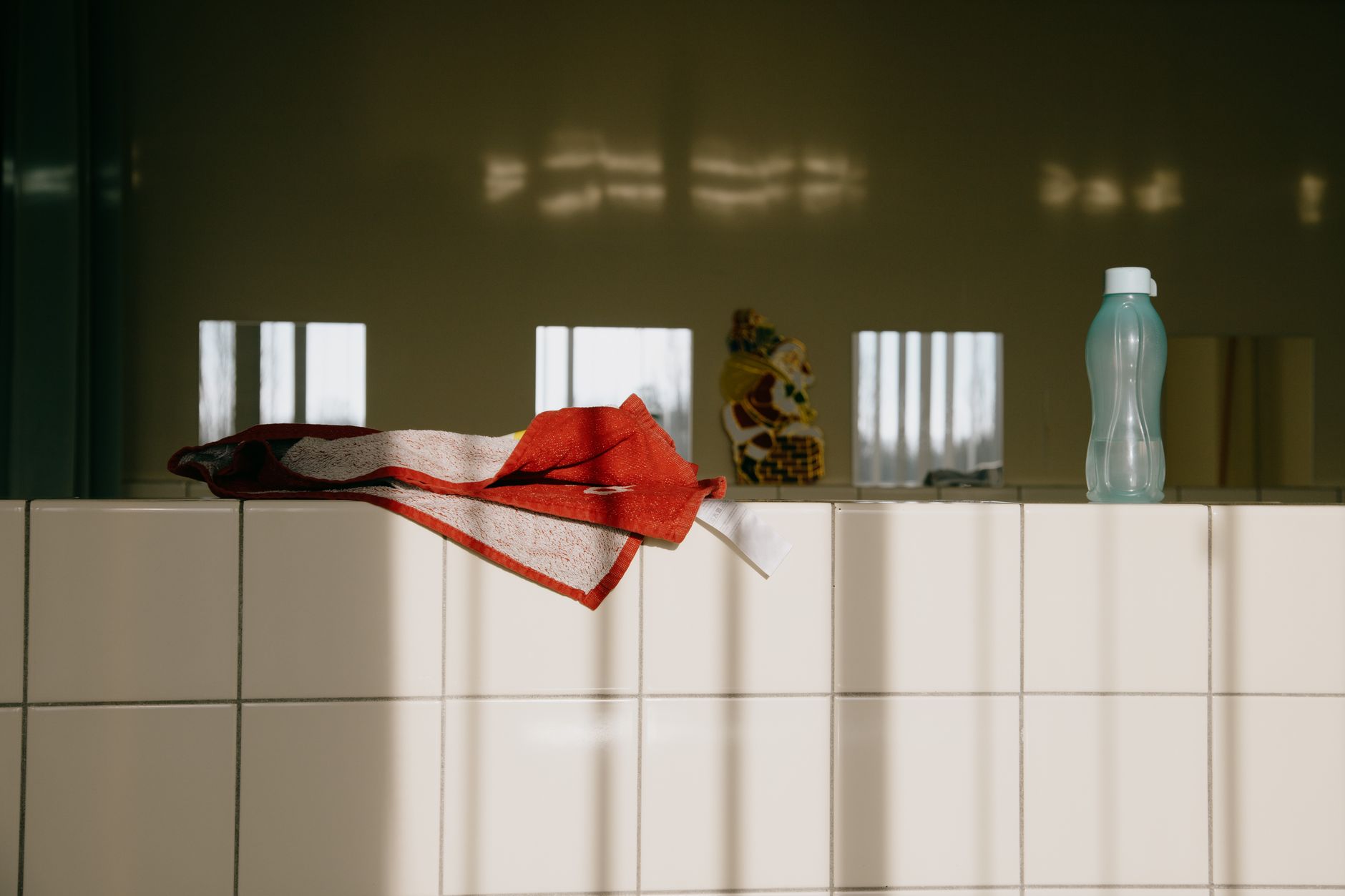A tidy bathroom shelf displaying infant acetaminophen drops, ibuprofen suspension, and a bottle of baby aspirin with a red cross overlay, bright natural light emphasizing safety labels