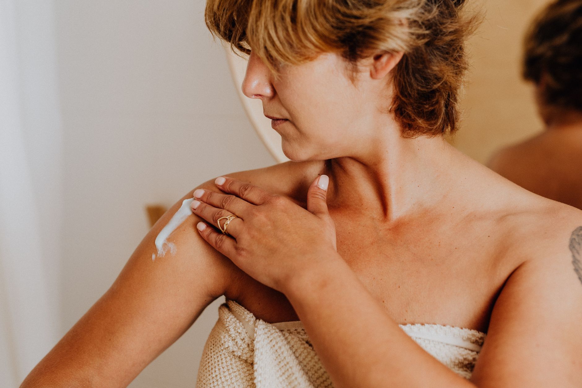 Close‑up of a hand spreading Bengay gel on a shoulder, showing the cooling effect as a faint mist