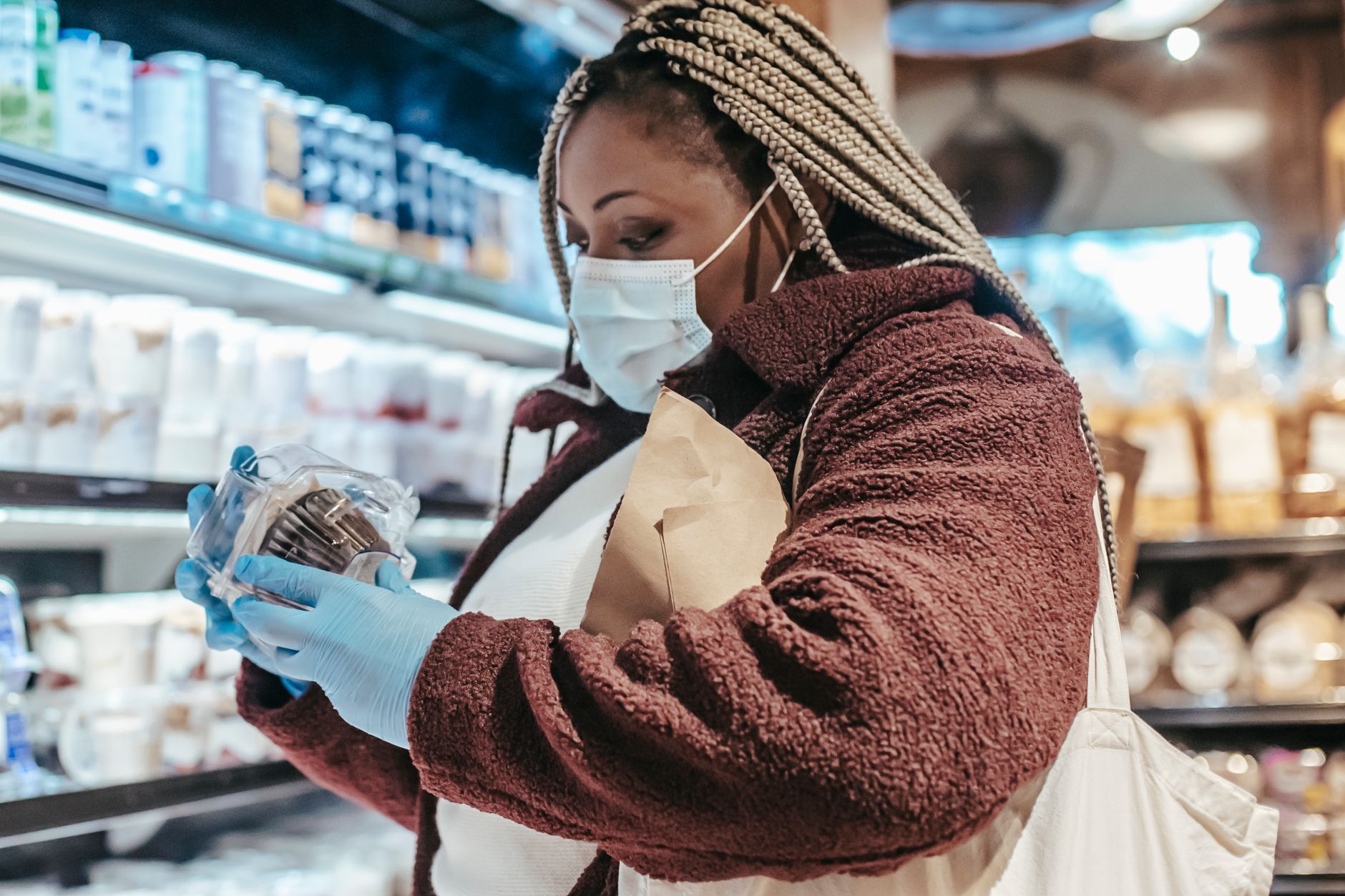 A pregnant woman looking thoughtfully at a food label in a grocery store aisle, focusing on ingredients.