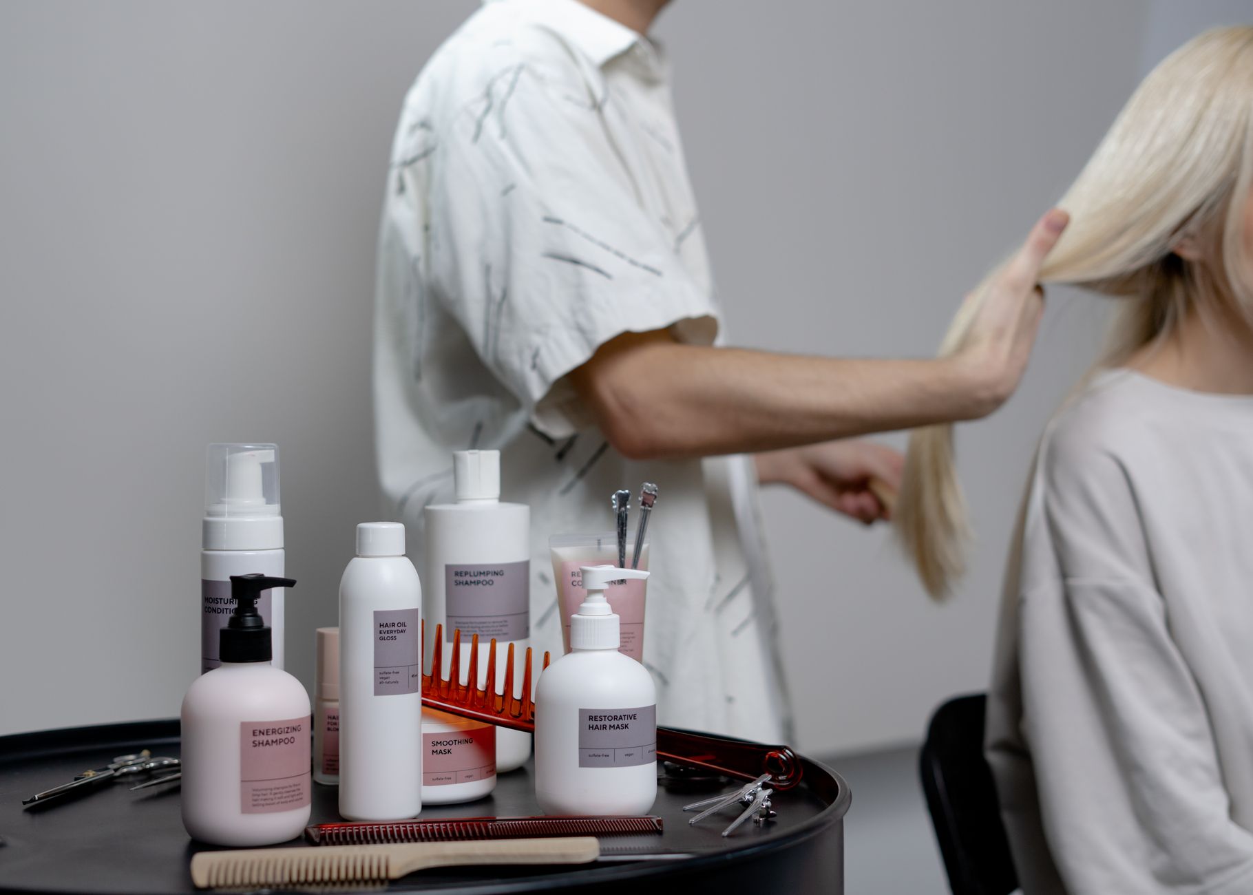 A salon technician applying Brazilian Blowout solution to a client's hair, emphasizing careful application and ventilation