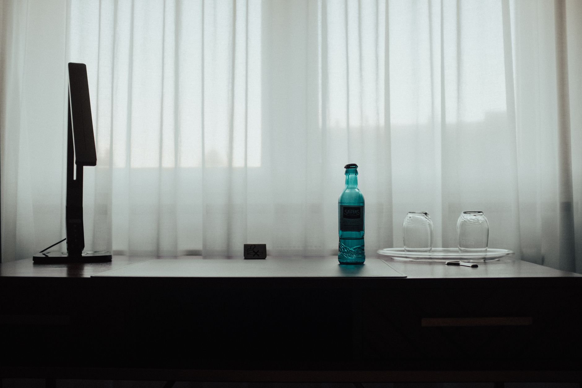 A tidy bathroom shelf displaying a bottle of Rocephin, a glass of water, and a pregnancy book, soft natural light emphasizing the calm setting