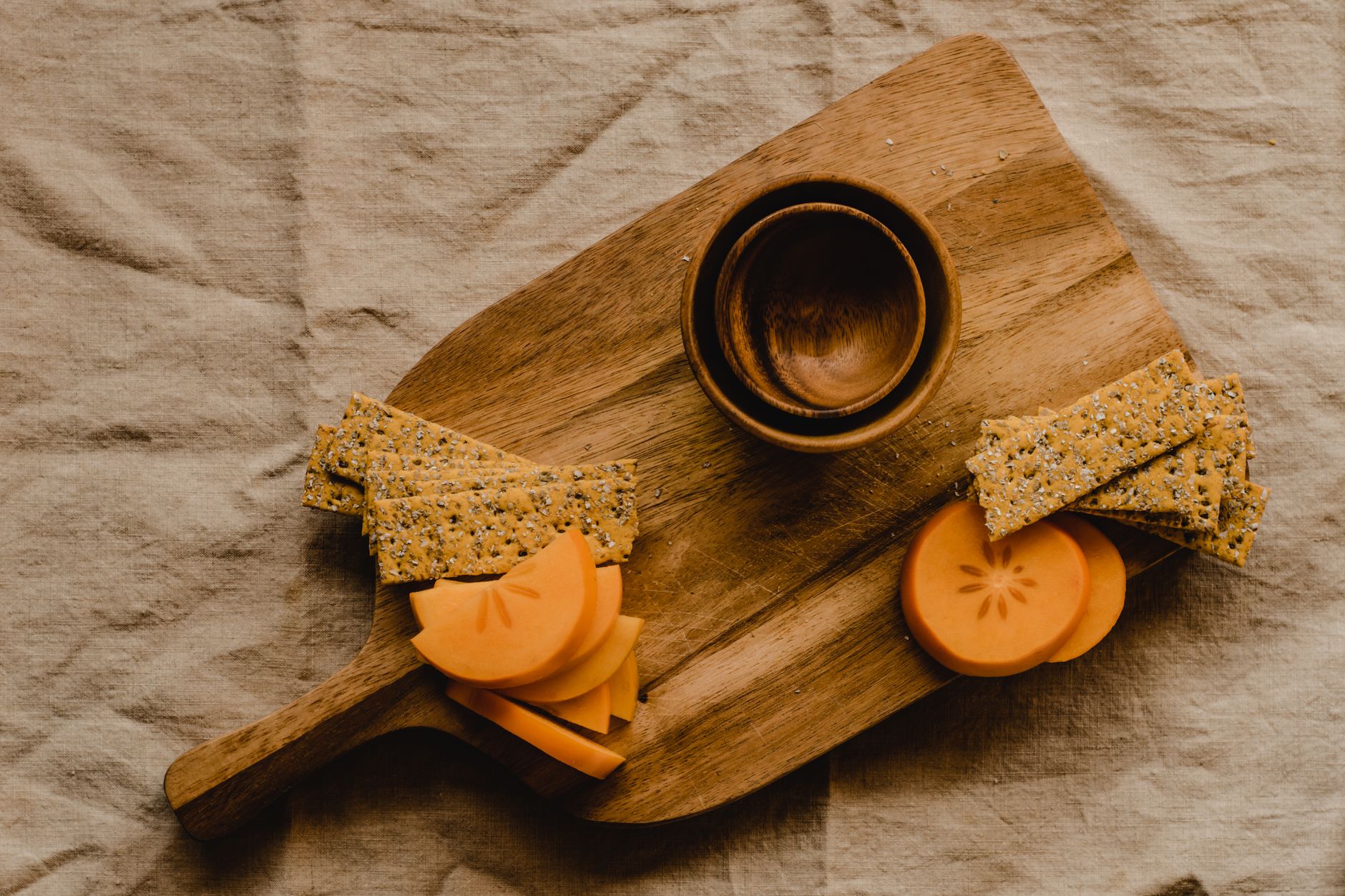 a selection of healthier snack alternatives for pregnant women, including whole grain crackers, fruit slices, and unsalted pretzels, arranged on a wooden board