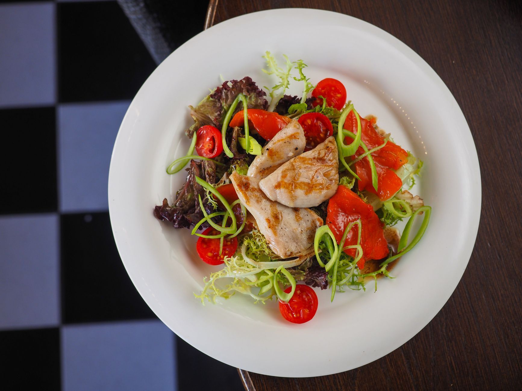 brightly lit fast‑food salad bar with various fresh greens, sliced strawberries, grilled chicken strips, and a small bottle of vinaigrette, emphasizing healthy choices for pregnant diners