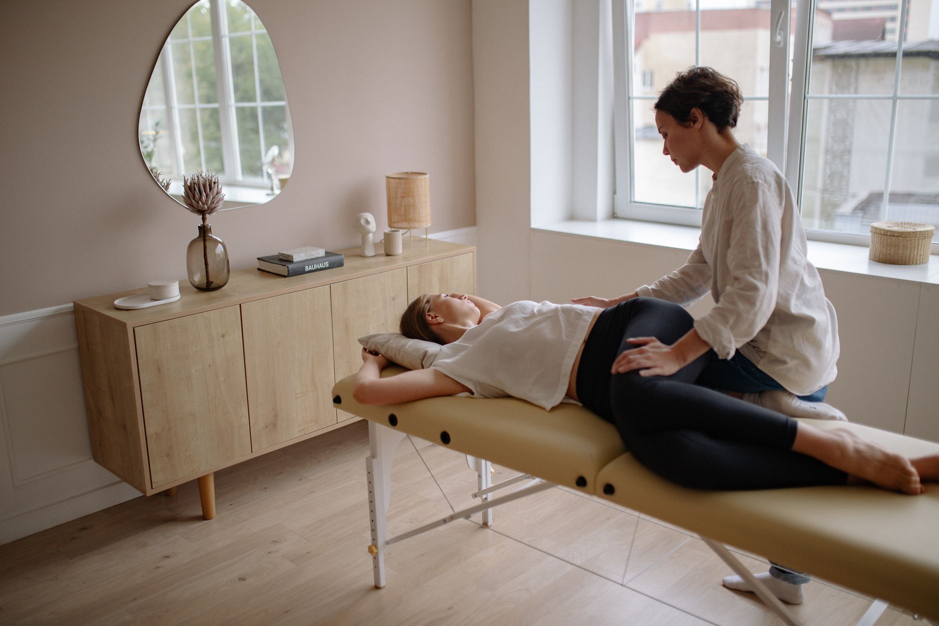 A chiropractor's hands gently adjusting the lower back of a pregnant woman lying on a specialized pregnancy table