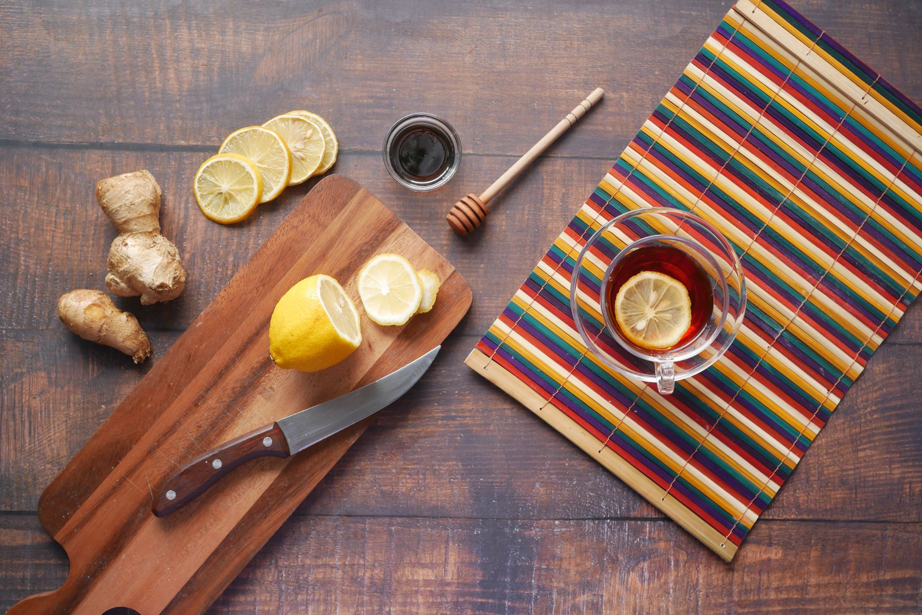 Assortment of pregnancy-safe sore throat remedies including honey, lemon, ginger, a mug of chamomile tea, and a box of herbal lozenges on a rustic wooden table