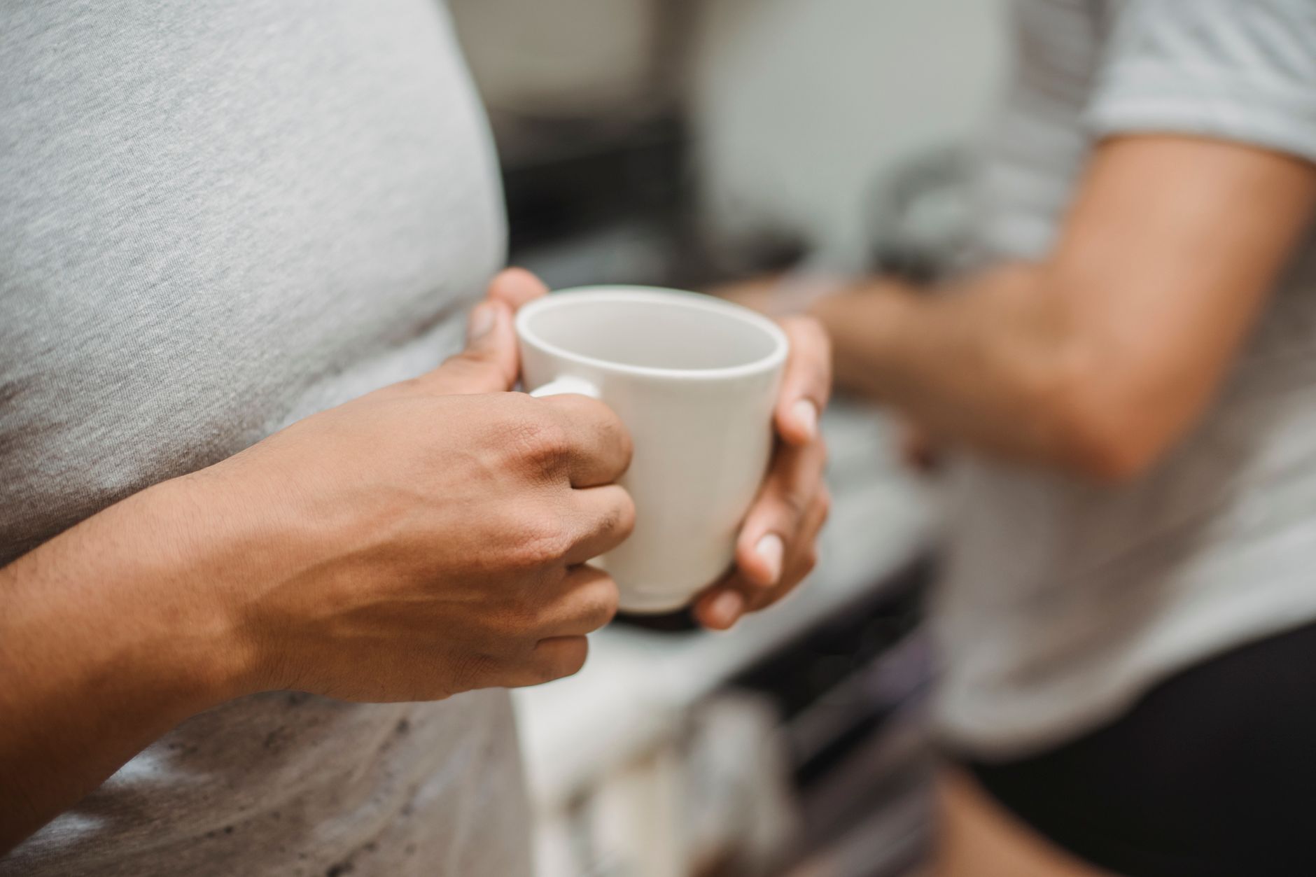 A pregnant woman's hands gently holding a warm mug of herbal tea, with a blurred background of a cozy living room