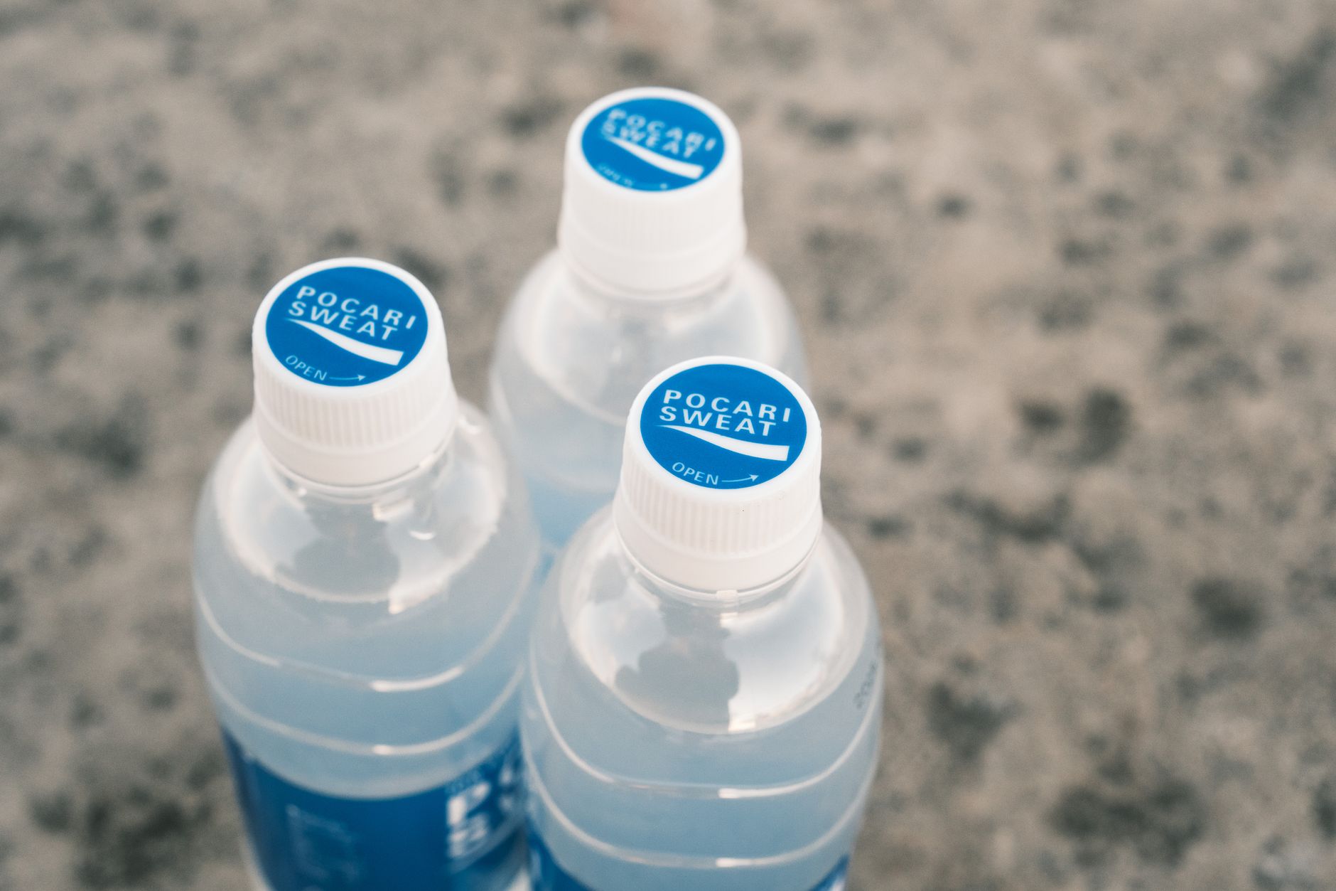 A side-by-side comparison of three bottled water brands—Nestlé Pure Life, Aquafina, and Evian—with their labels facing forward, placed on a wooden table with a travel towel and a pregnancy-safe hand sanitizer.