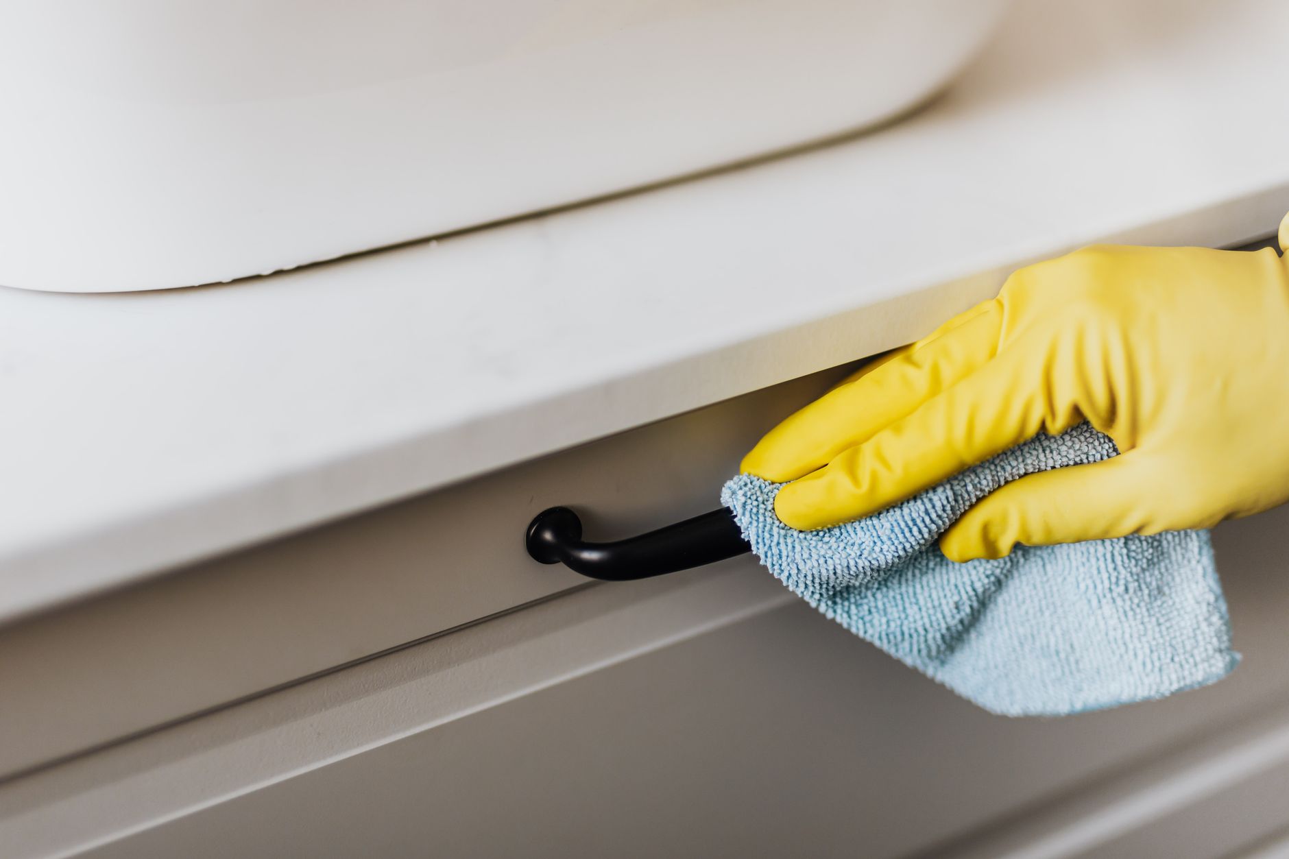 A well‑ventilated bathroom with an open window, a bottle of natural cleaning wipes, and a pregnant woman wearing gloves, illustrating safer cleaning practices