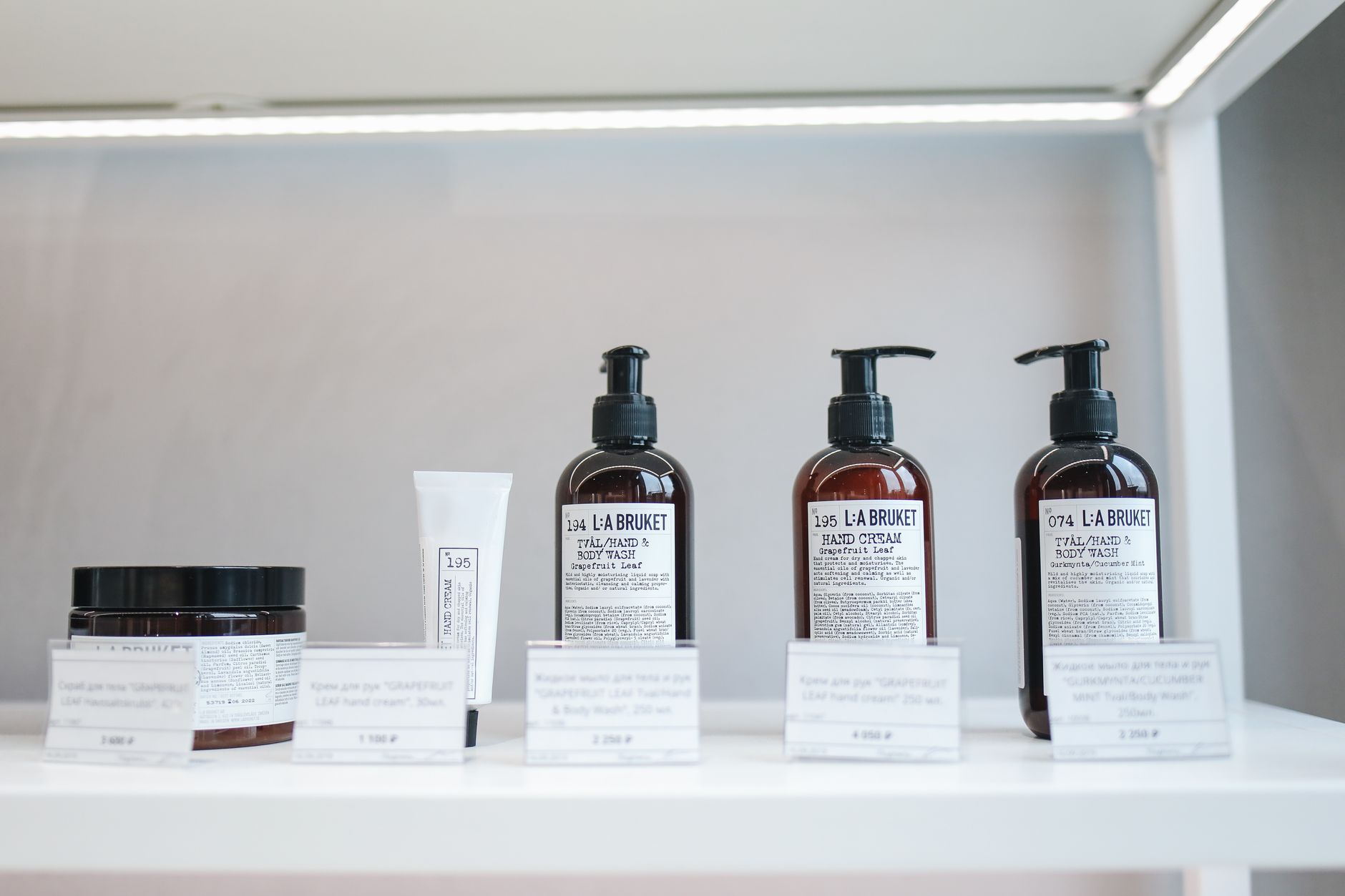 A clean bathroom shelf displaying a range of gentle skin-care products, including a hydrocortisone 0.5% tube, a bottle of aloe vera gel, and a tub of moisturising cream, all bathed in soft natural light