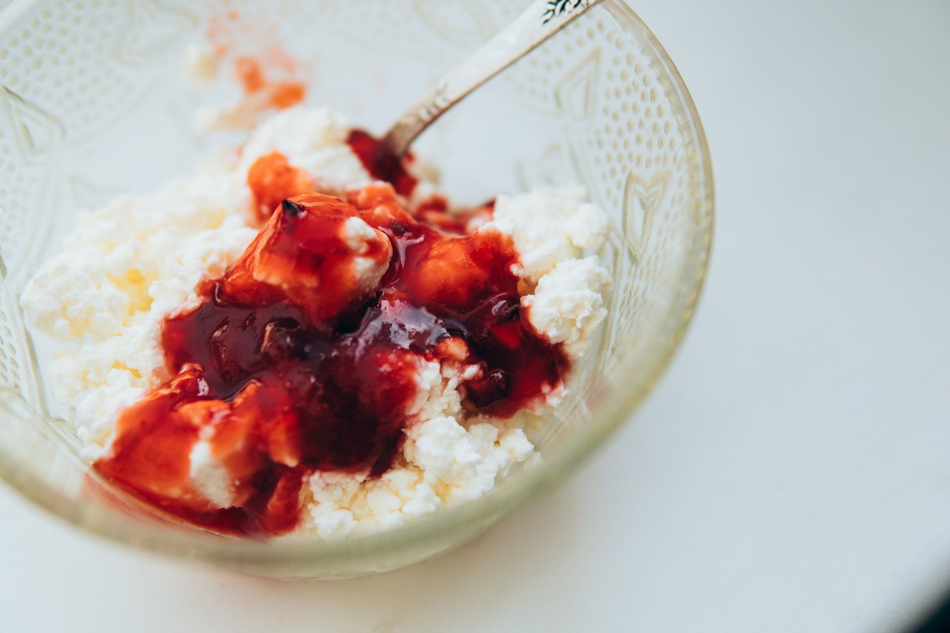 a slice of cotija cheese next to a measuring spoon and a small bowl of sliced strawberries, illustrating portion control for a pregnant woman, 95‑character alt text