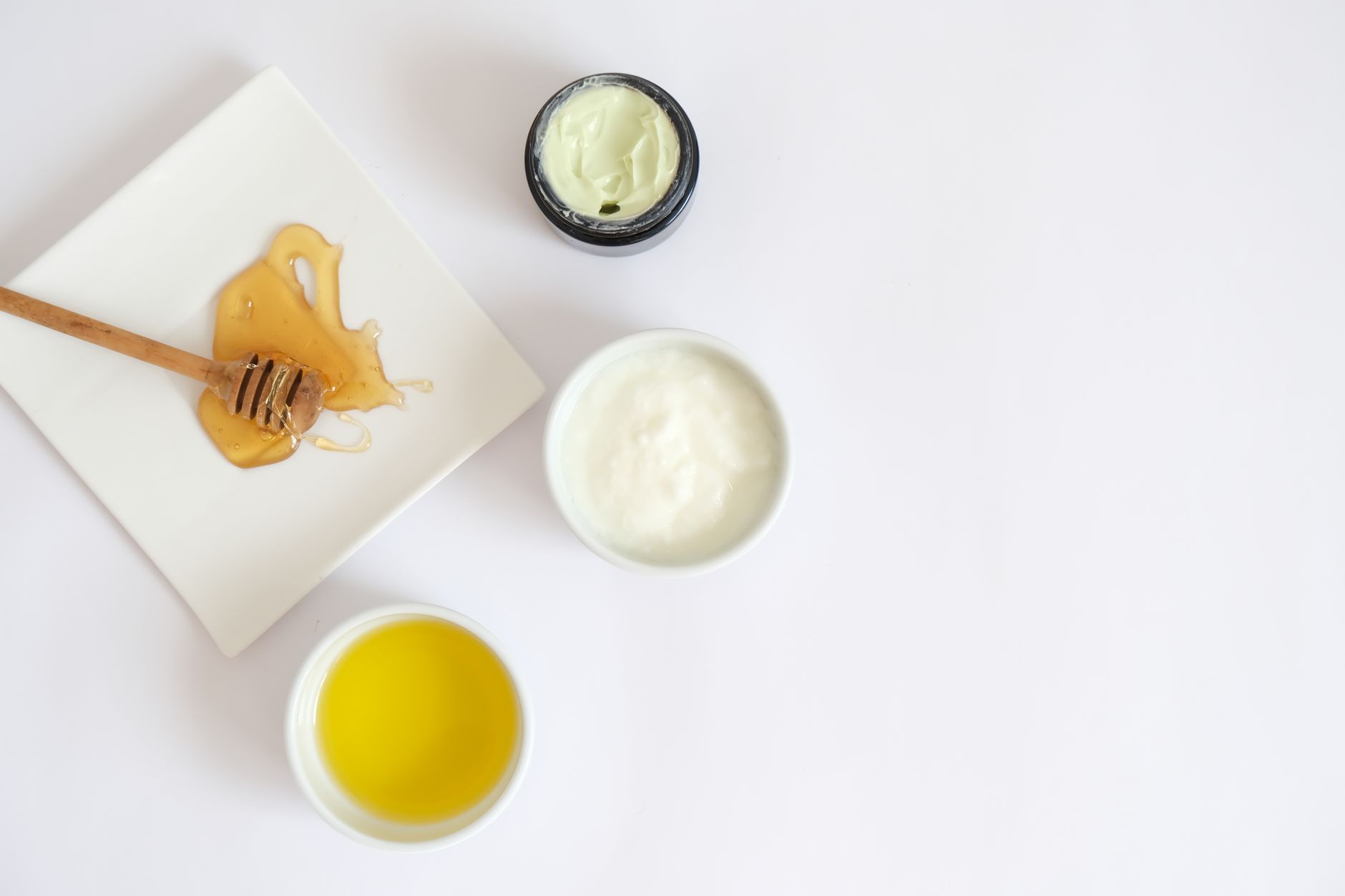A selection of pregnancy-safe cold and cough remedies including a box of throat lozenges, a bottle of saline nasal spray, and a jar of honey, arranged on a light-colored surface