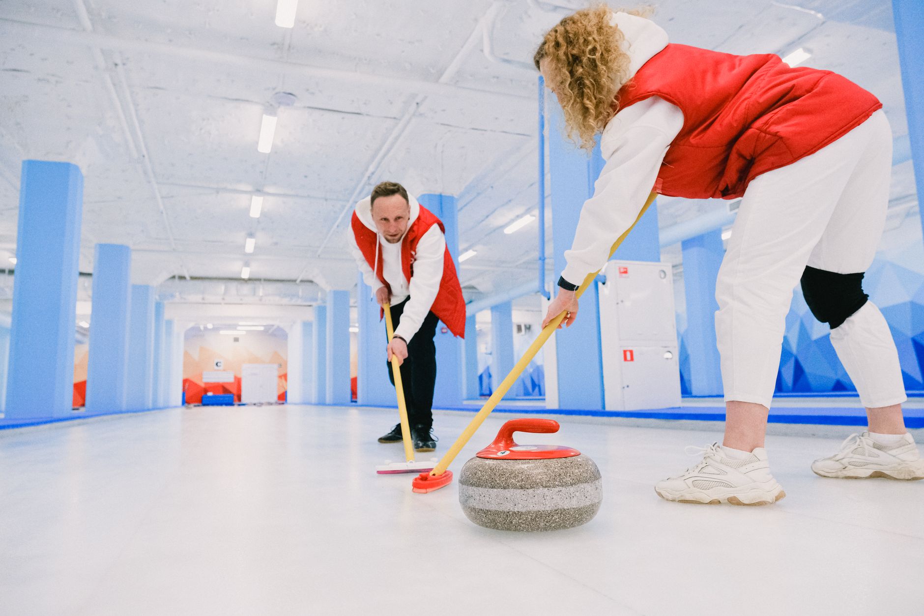 Pregnant woman drinking water from a bottle on the sidelines of a curling game