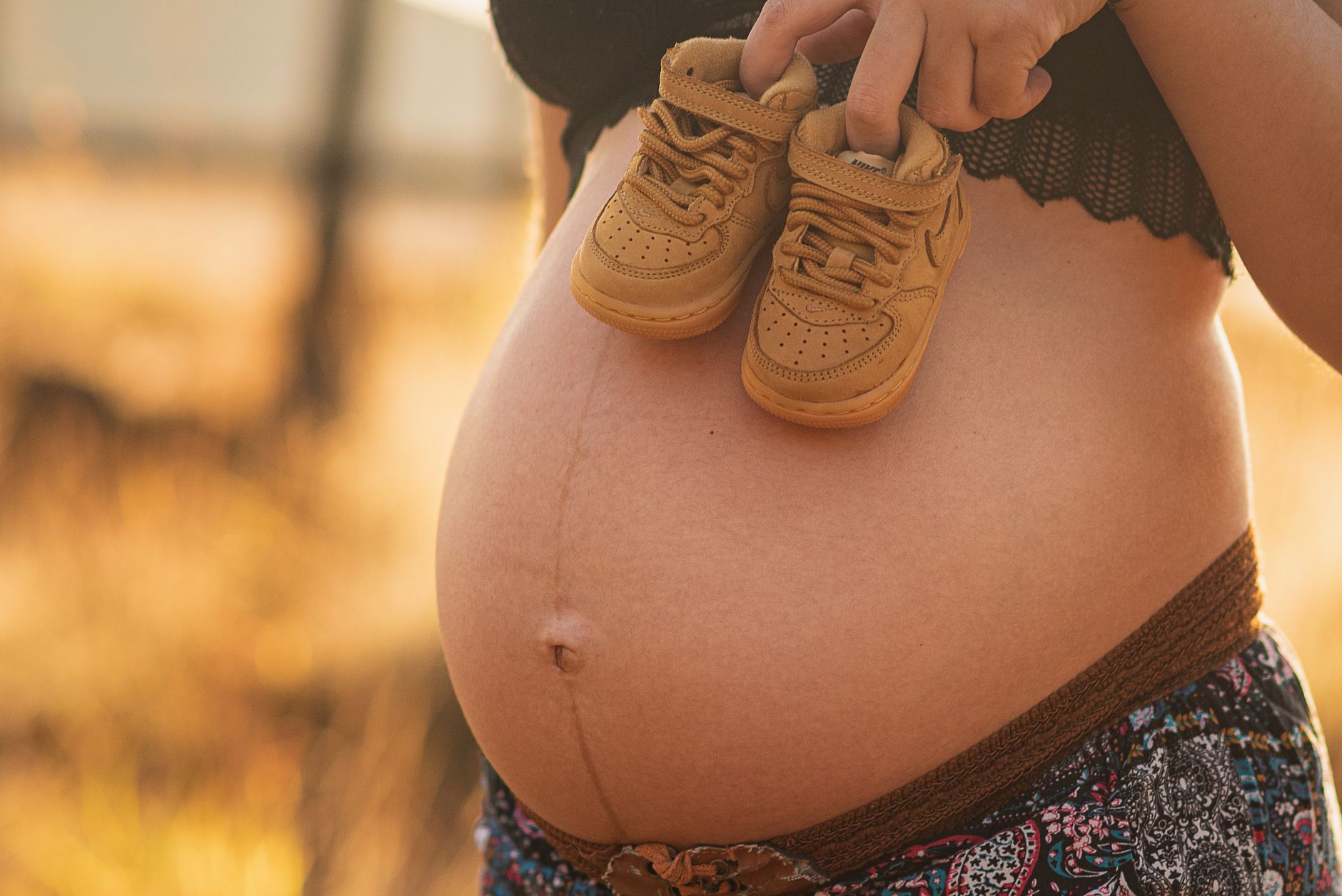 close-up of a pregnant woman's hands holding a water bottle and a bike helmet