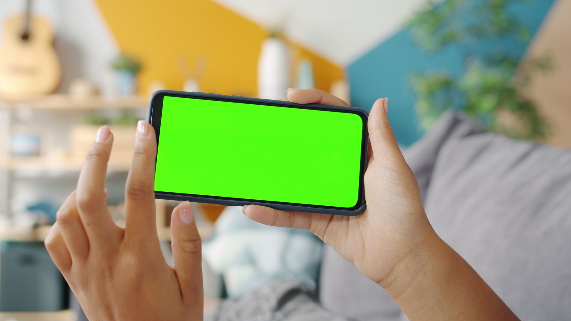 A person's hands holding a smartphone, scrolling through health information, with a blurred background of a cozy living room and a warm drink.