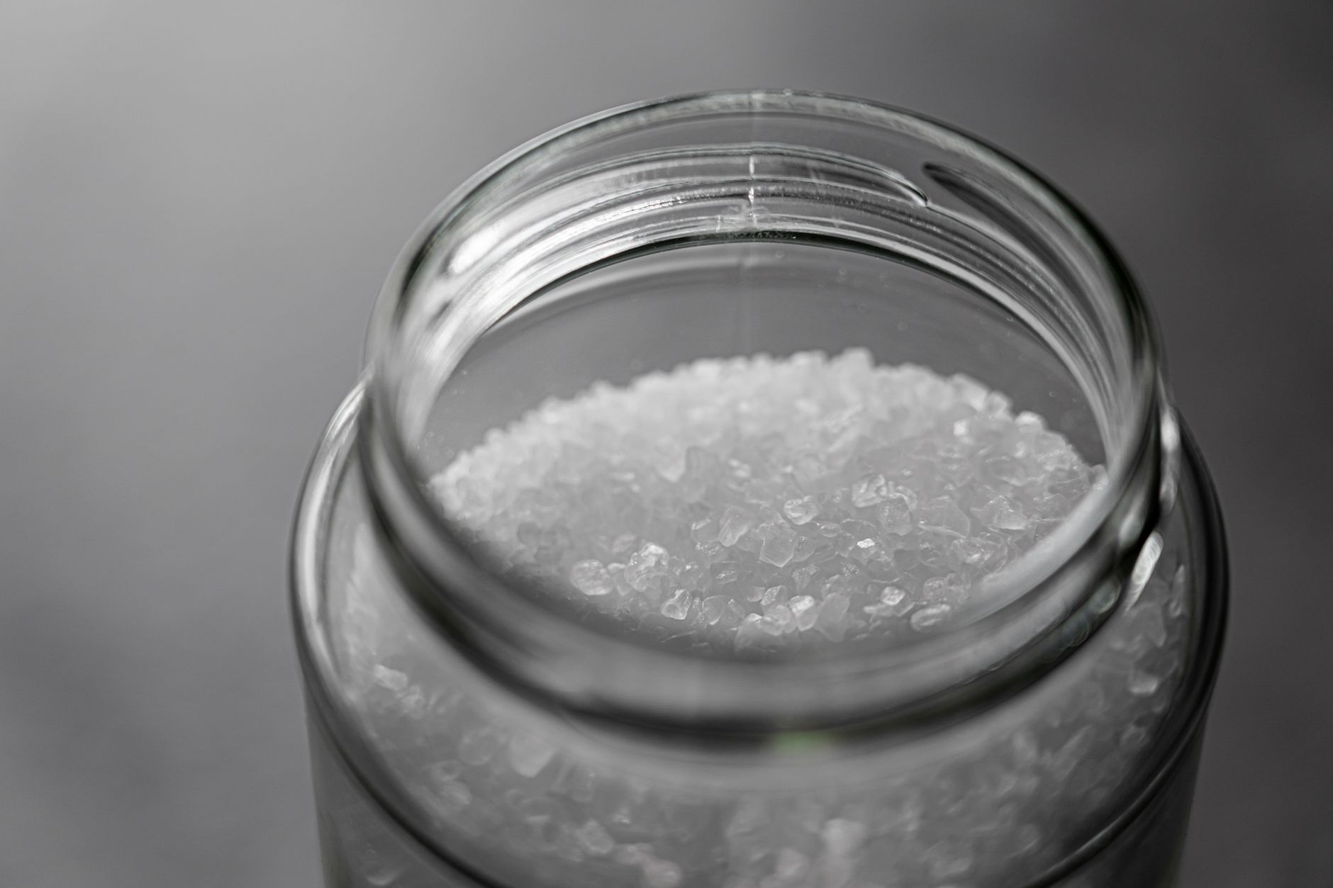 A close‑up of a clear glass measuring cup filled with two cups of crystalline Epsom salt, ready to be added to a bathtub, illustrating the recommended dosage for pregnant users