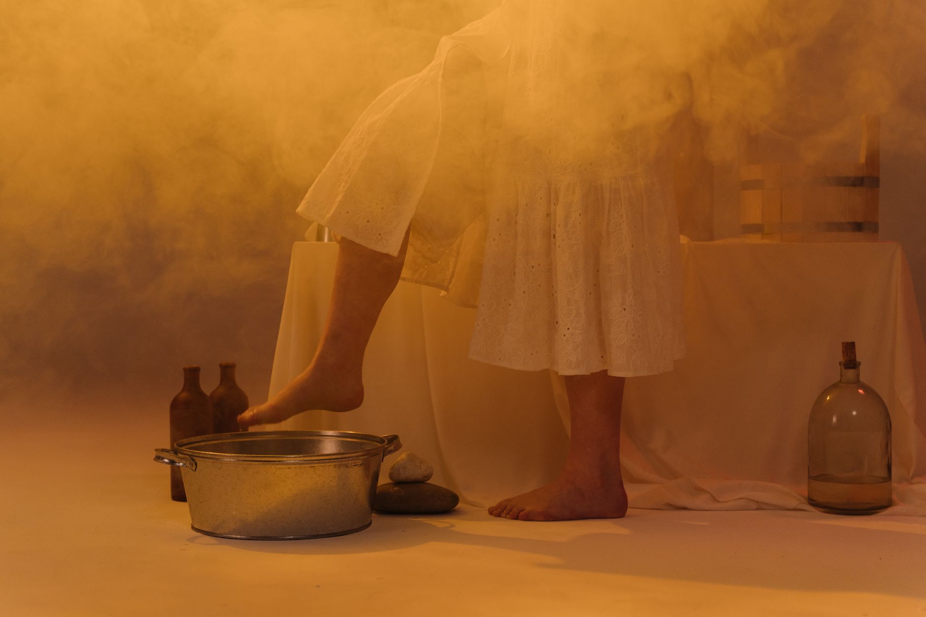 A pregnant person sitting comfortably with a foot basin filled with warm water and a handful of Epsom salt, illustrating a safe foot soak routine