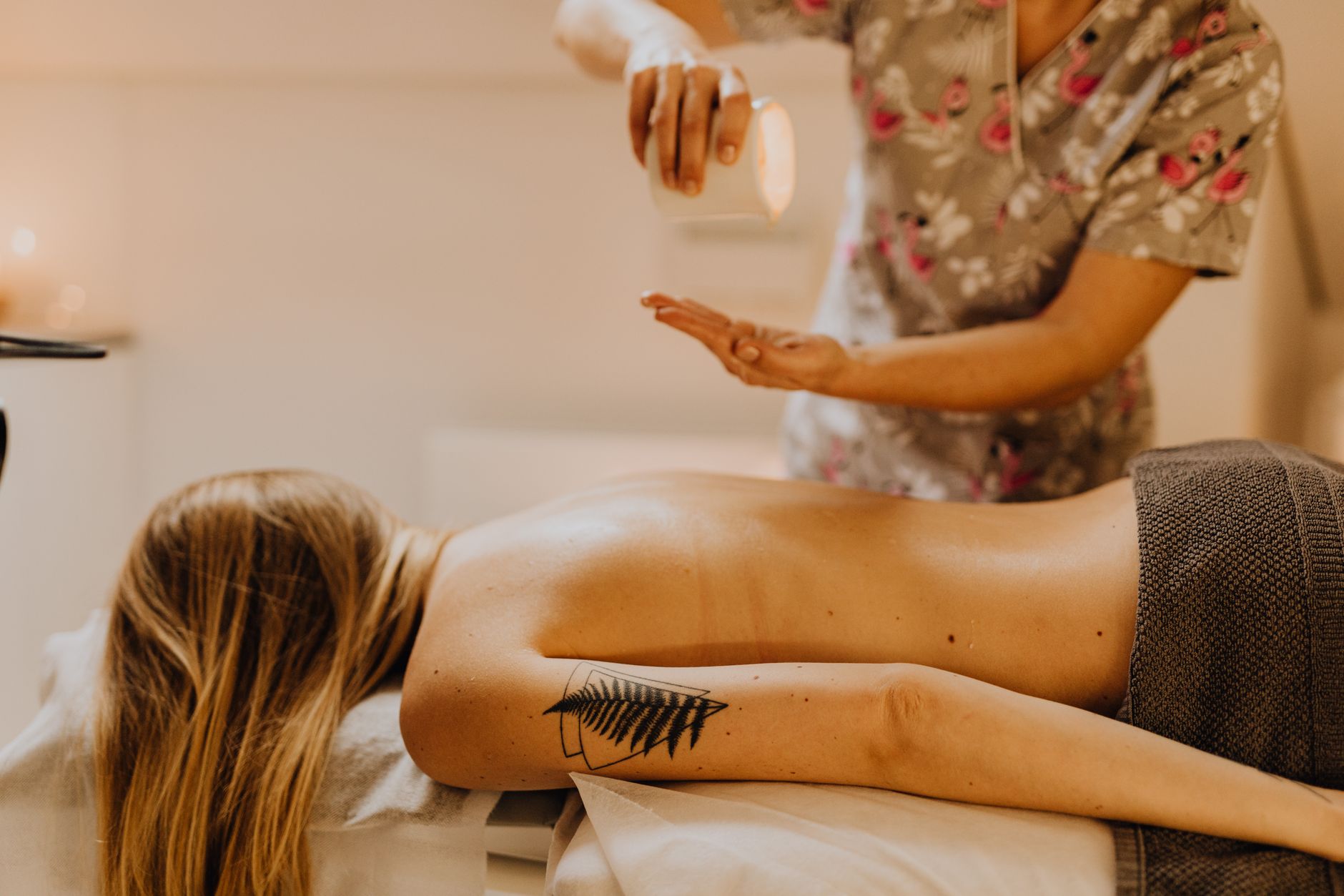 A serene prenatal massage setting with a therapist applying a light blend of diluted eucalyptus oil on a pregnant client's shoulders, soft candlelight and calming colors in the background
