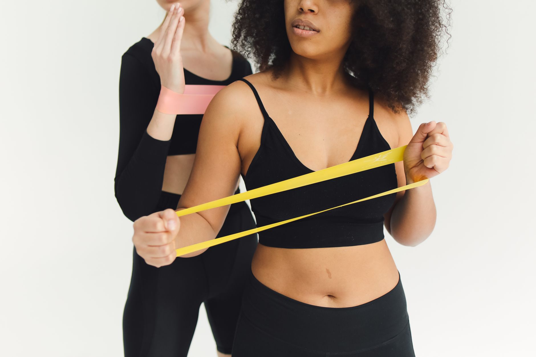 A pregnant woman using a resistance band in a bright studio, demonstrating a low‑impact modification of a typical F45 circuit, with a heart‑rate monitor visible on her wrist.