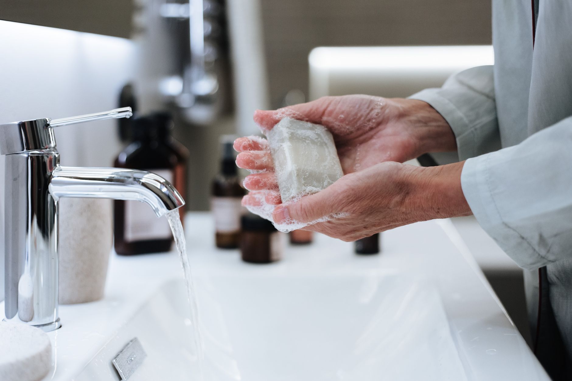 hand washing with soap and water at a sink, bubbles forming, with a subtle calendar showing October in the background, emphasizing flu‑season hygiene