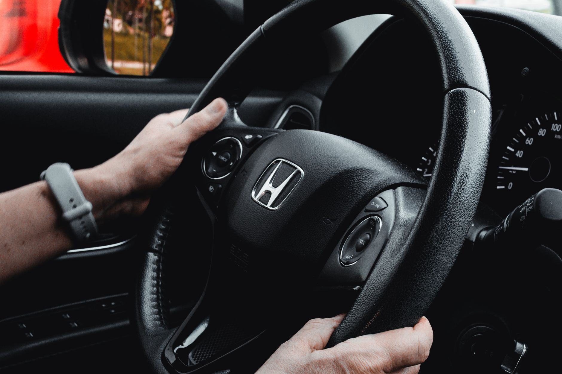A person's hands resting on an ergonomic forklift steering wheel with controls, emphasizing safe operation