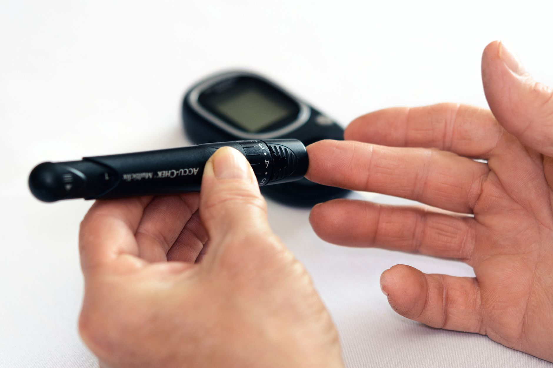 A hand holding a fruit rollup next to a glucose monitor display, showing a pregnant woman's careful tracking of blood sugar after a snack