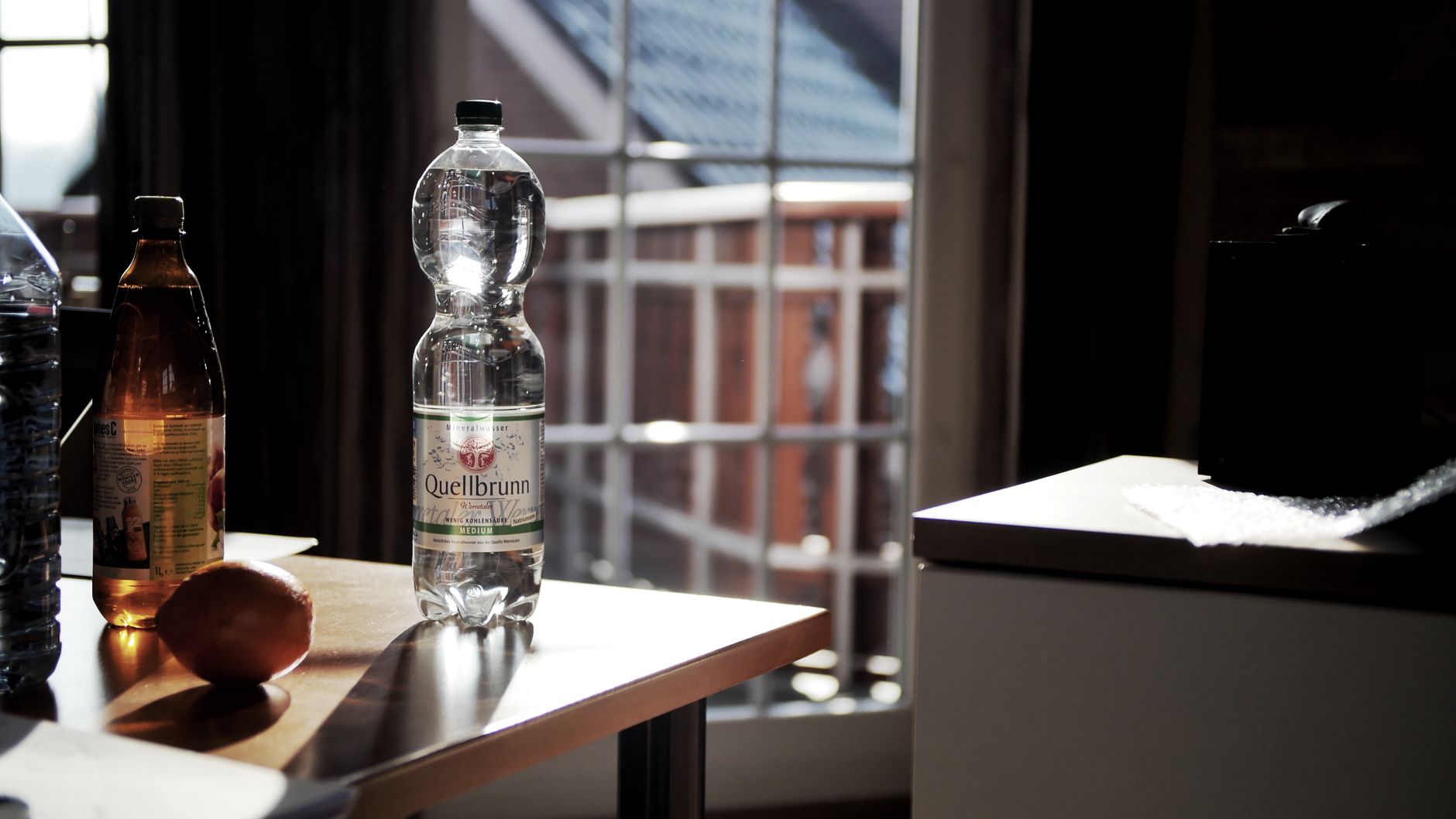 a sleek bottle of Pedialyte unsweetened sitting next to a glass of water, illustrating a low‑sugar electrolyte alternative for pregnant individuals