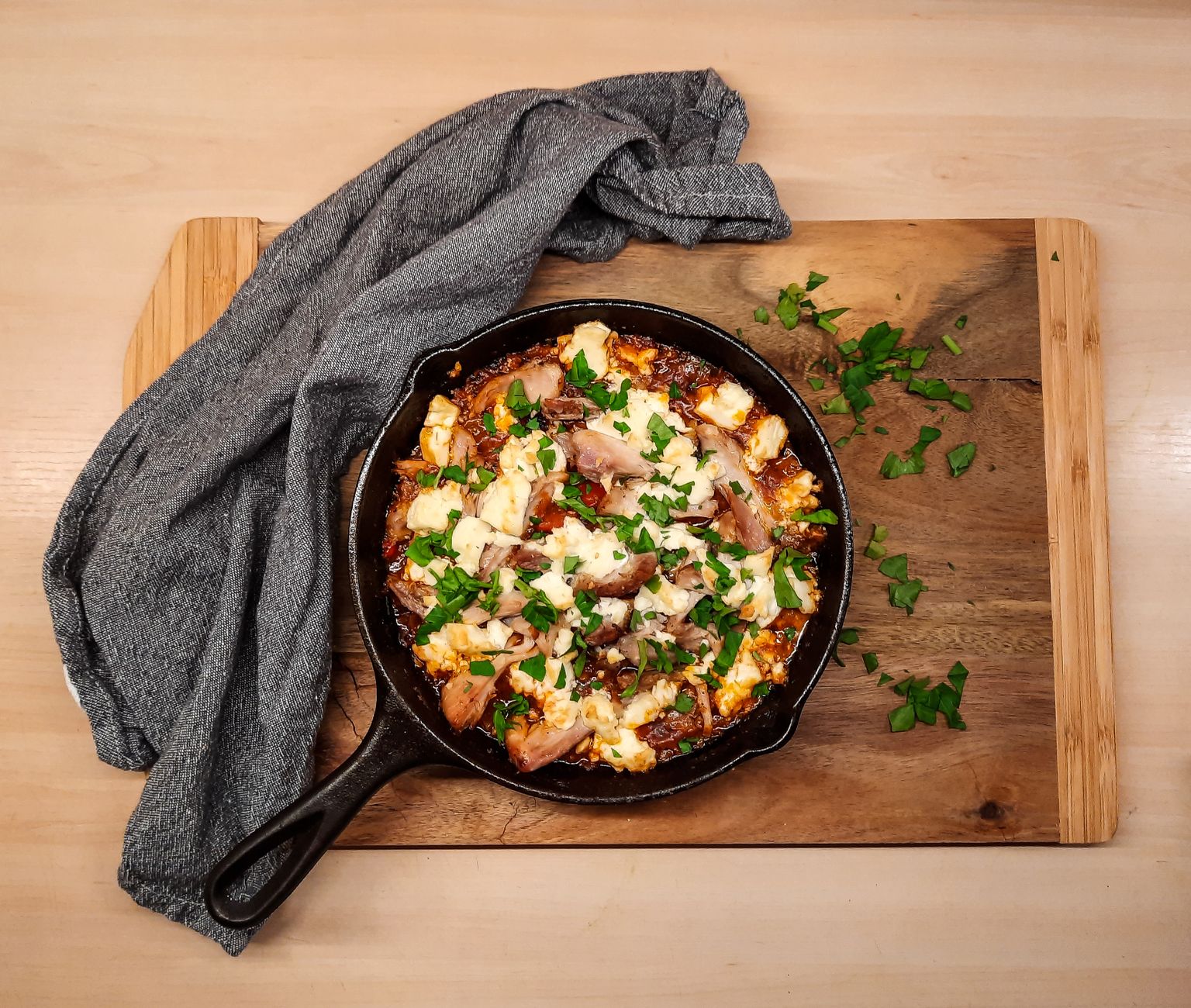 A skillet with melted goat cheese bubbling over a bed of roasted vegetables, showing a cooked dish that has reached a safe temperature