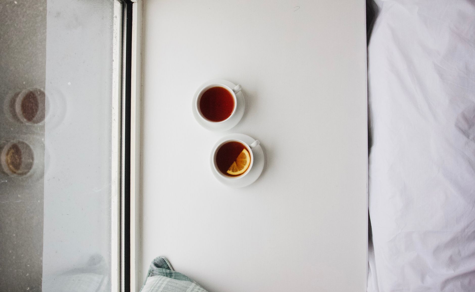 A variety of pregnancy-safe teas and warm drinks arranged on a kitchen counter, including ginger tea, decaf green tea, and a mug of warm lemon water.