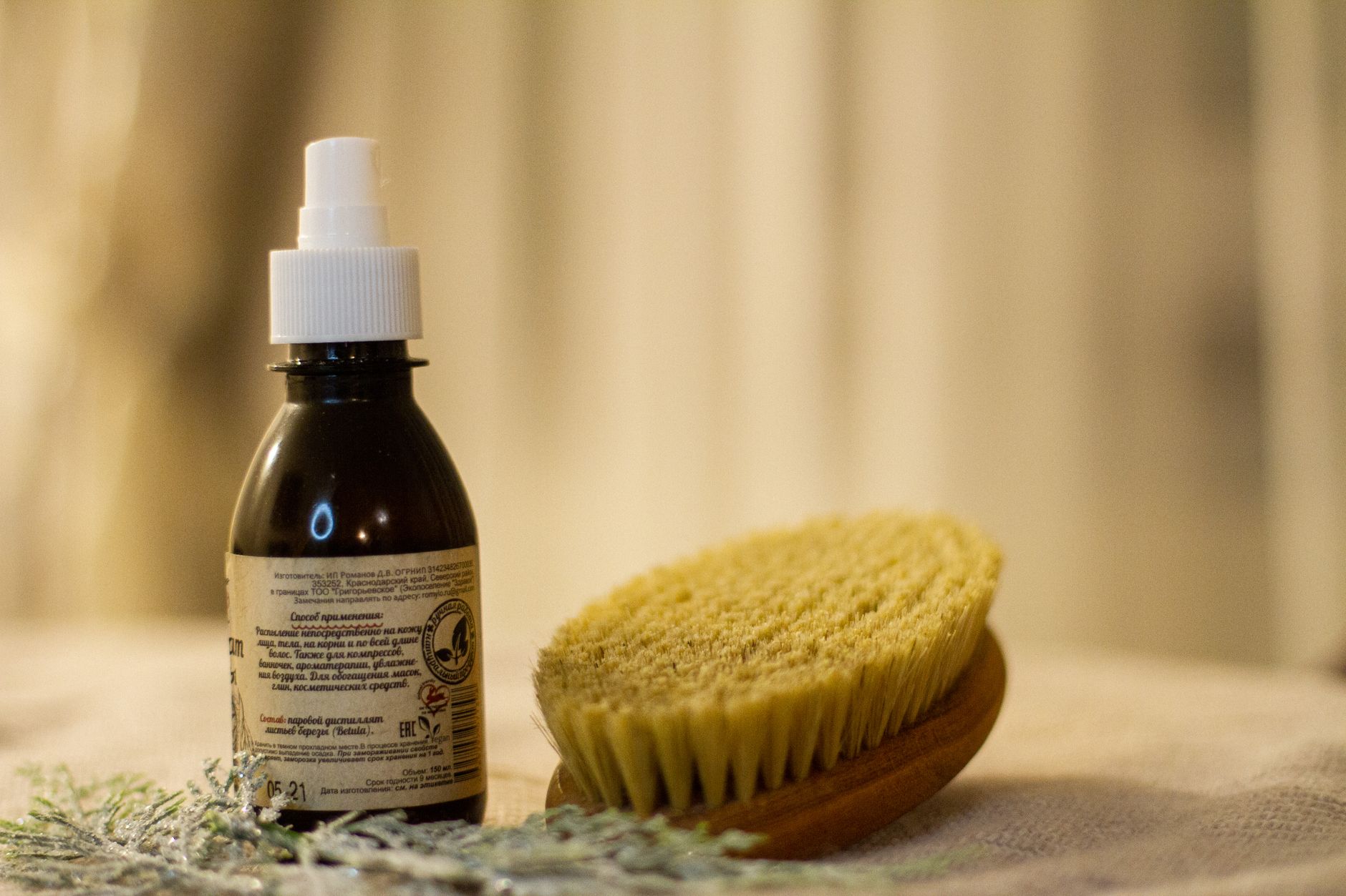 close‑up of a hair Botox bottle with a label showing natural ingredients like argan oil and keratin, placed on a wooden vanity beside a pregnancy nutrition book