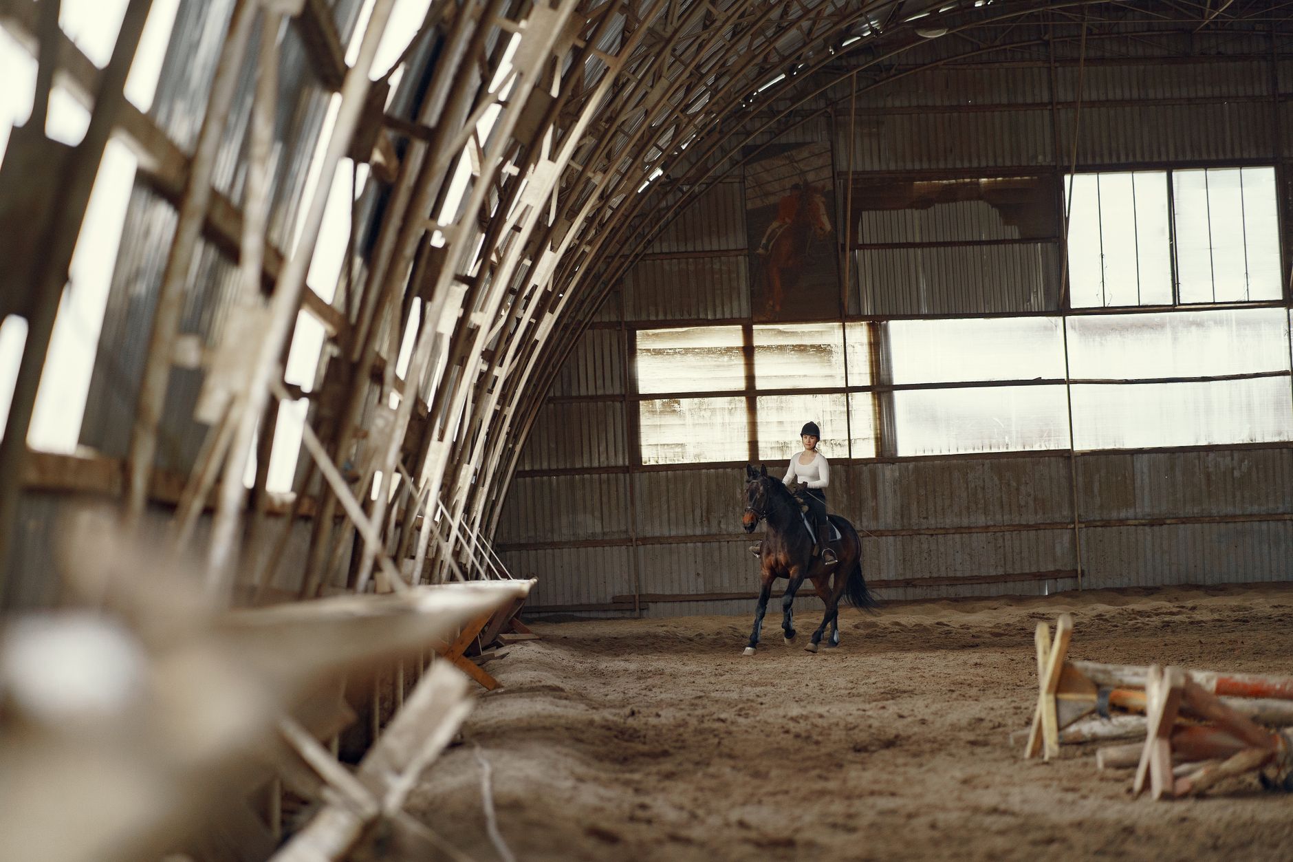 a serene indoor equestrian arena with a calm horse, a saddle, and a safety helmet placed beside a yoga mat, illustrating a transition from riding to safer prenatal activities