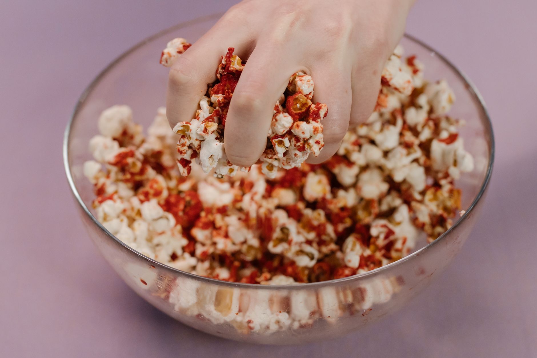 A bowl of plain popcorn sprinkled with a pinch of paprika, a healthier spicy snack alternative for pregnant women