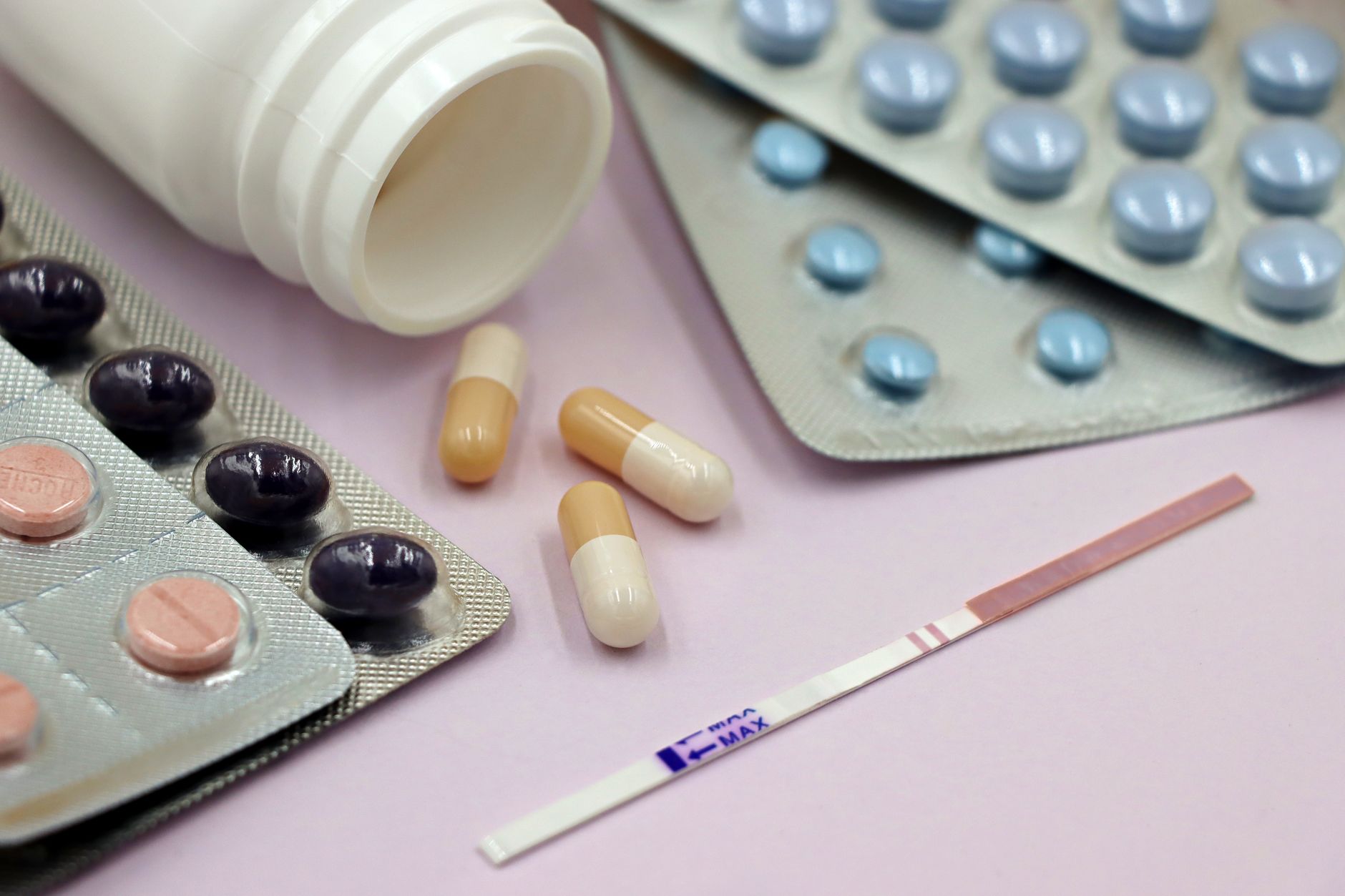a hand holding a blister pack of hydrocortisone tablets next to a pregnancy test, soft natural light emphasizing the contrast between medication and new life