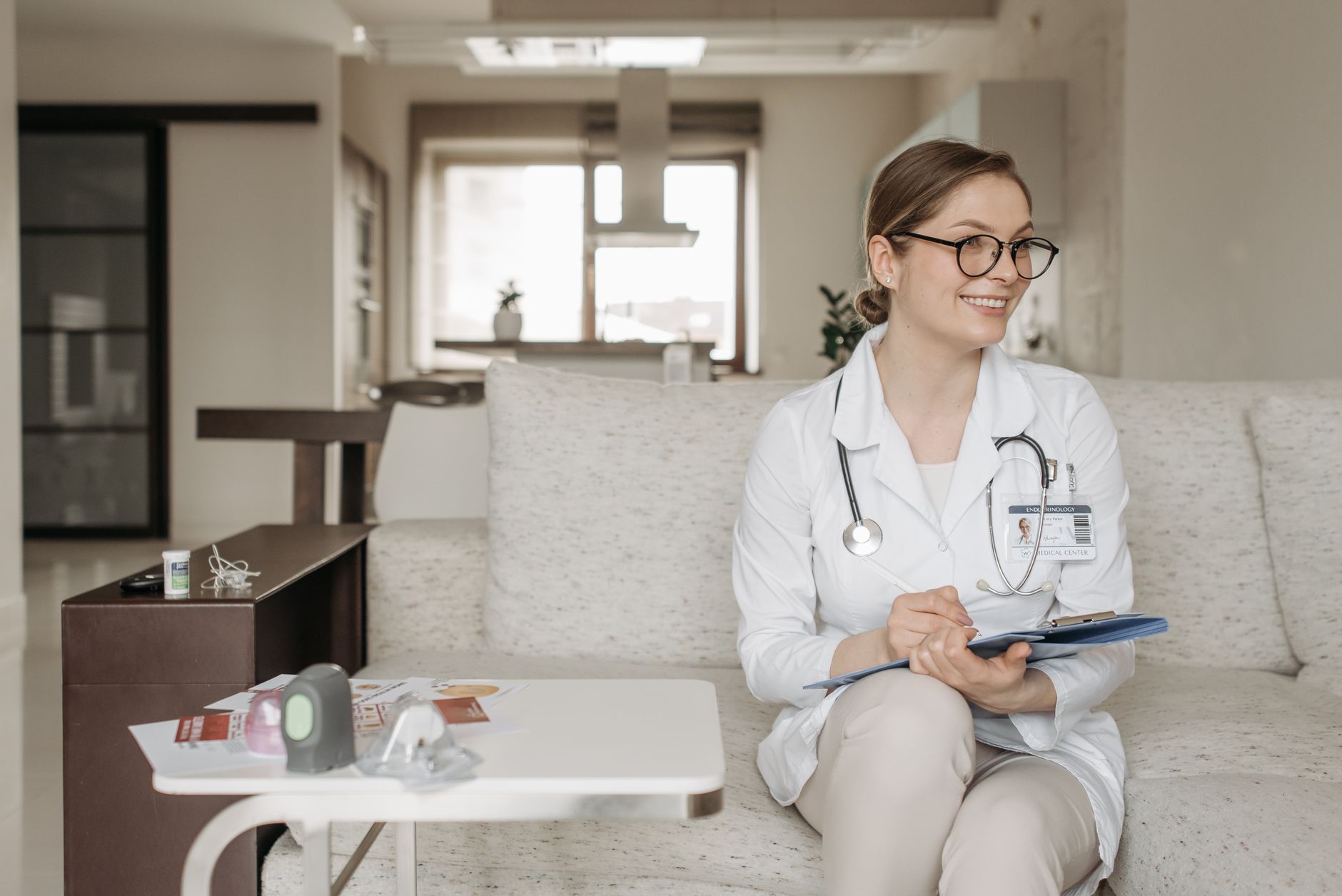 A calm prenatal care setting with a doctor discussing medication options with a pregnant woman, showing a clipboard with medication icons and a cup of ginger tea