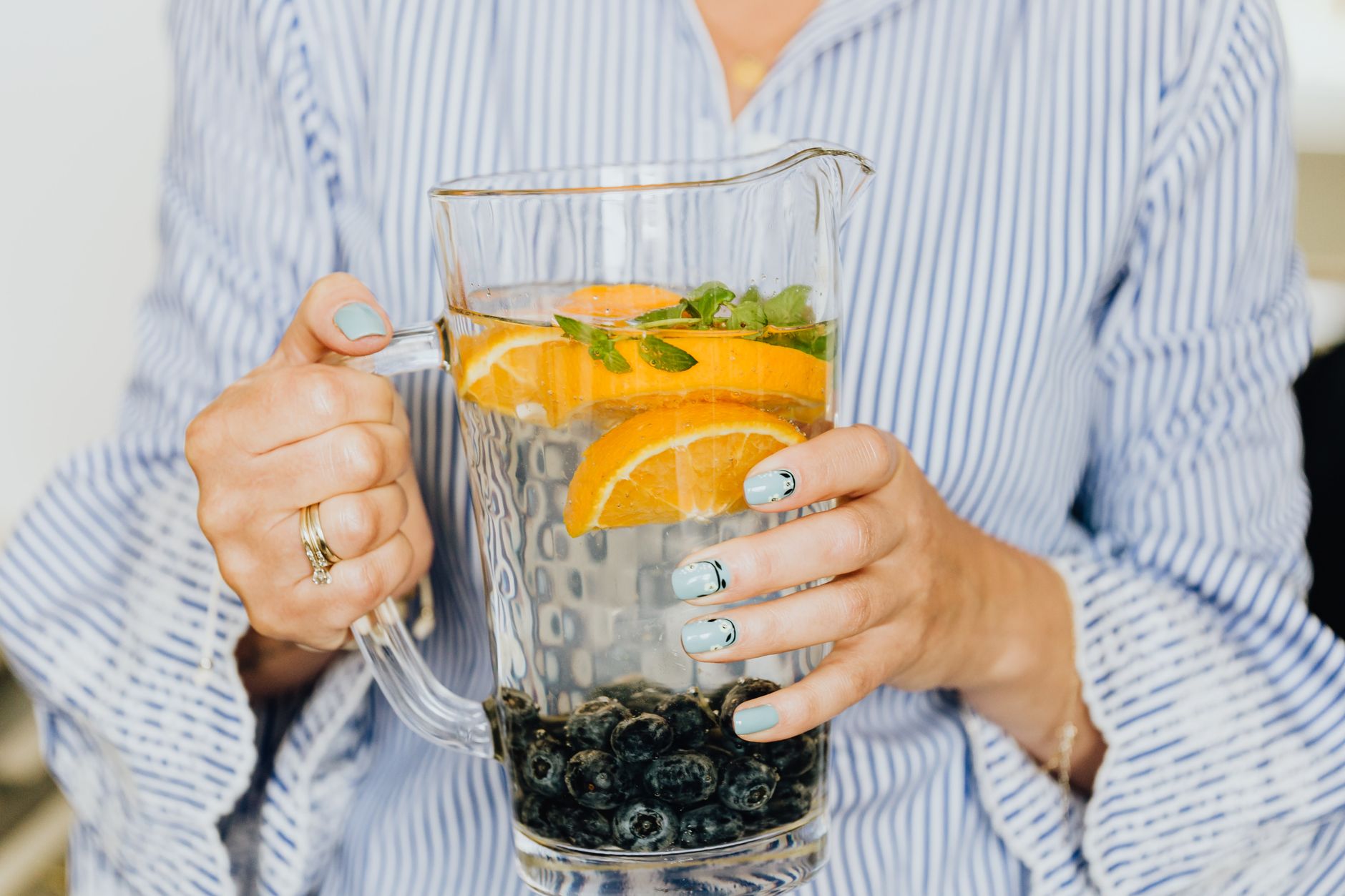 Close-up of a pregnant woman’s hands holding a glass of water with lemon slices