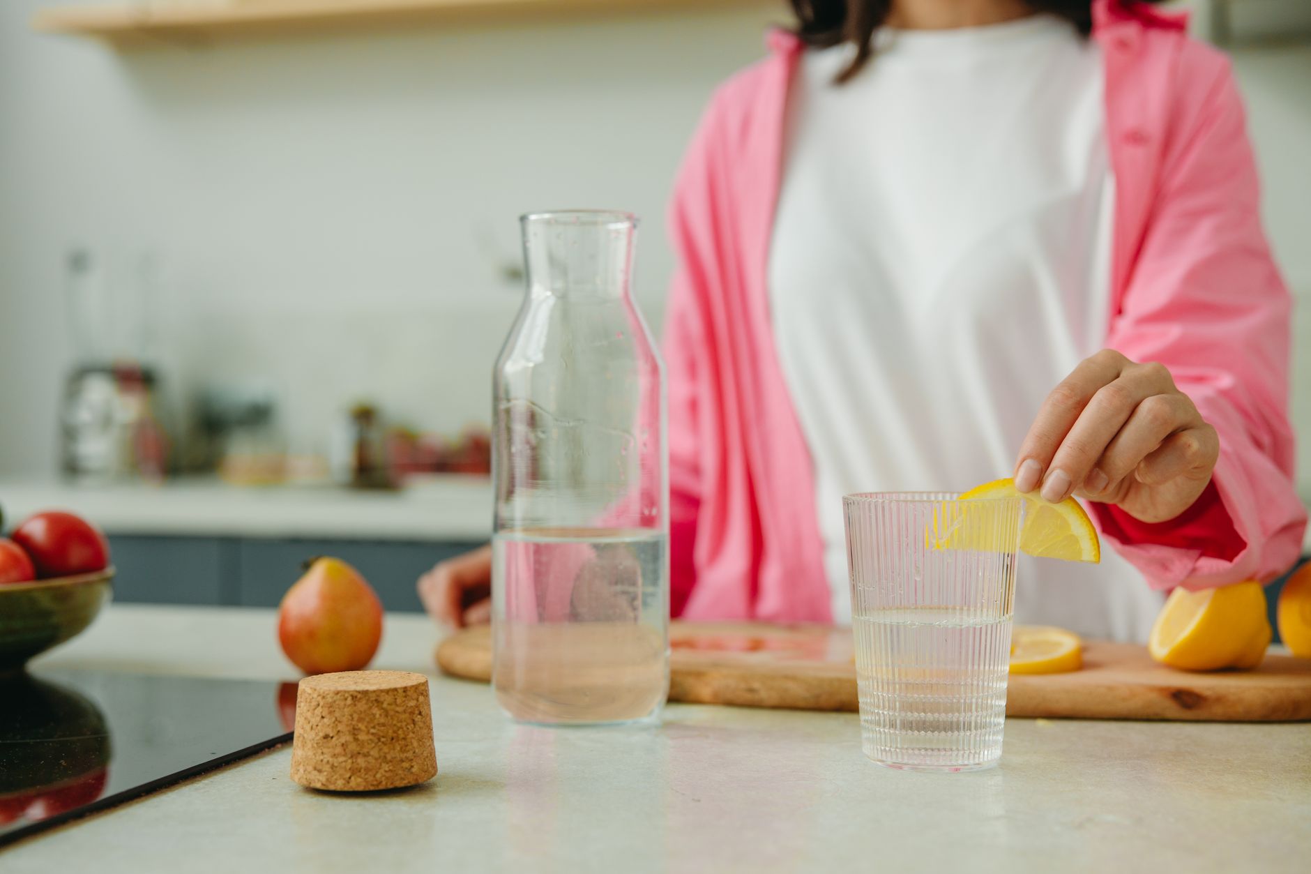 A pregnant woman sitting at a kitchen table with a pitcher of homemade oral rehydration solution, fresh lemon slices, and a digital scale for precise measurement, soft morning light casting gentle shadows