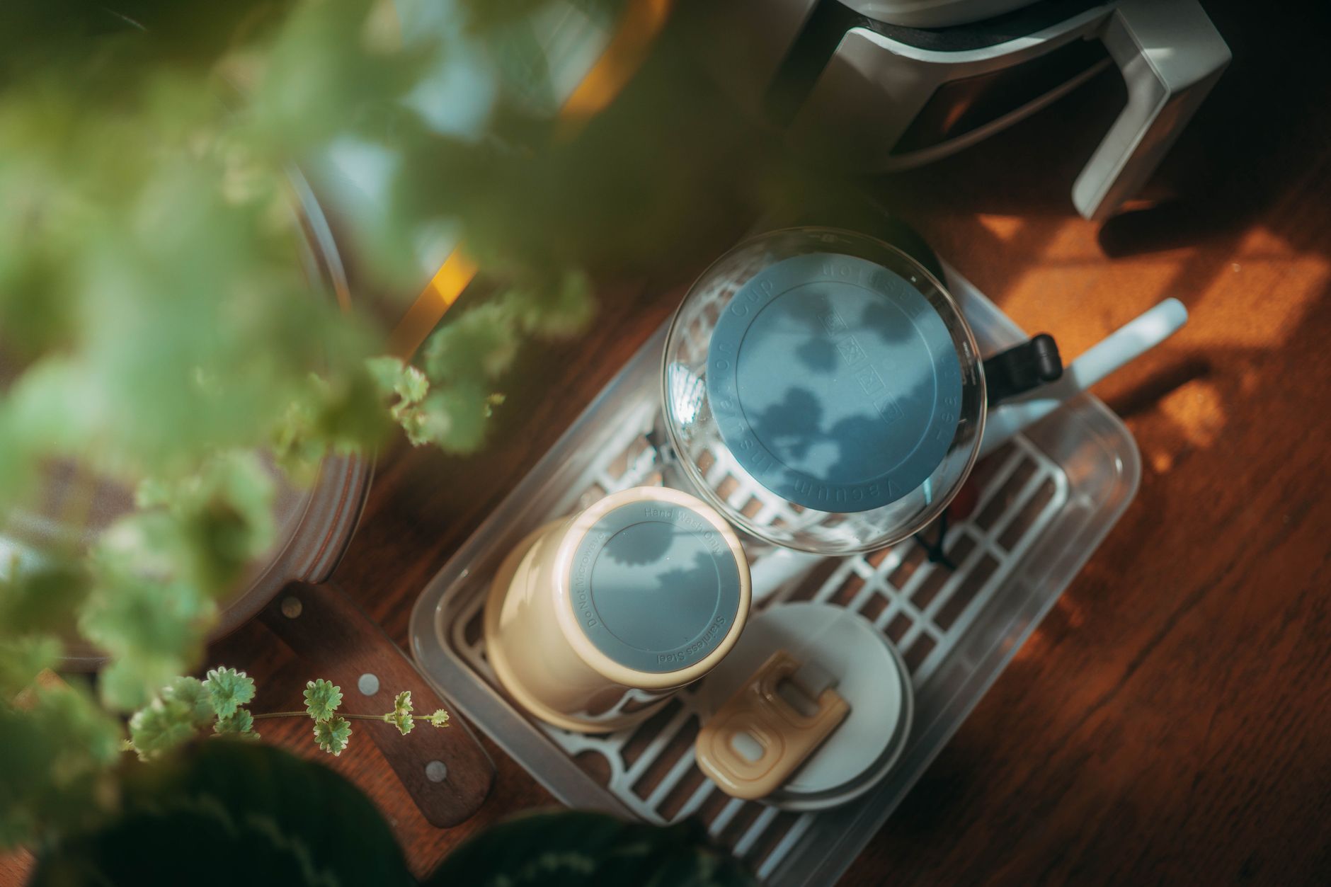 A calm nursery scene with a wooden feeding tray holding a sterilized bottle, a soft blanket, and a small potted plant, bright morning light
